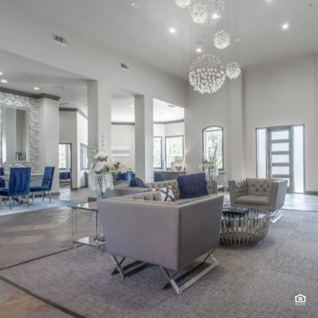 Luxurious and spacious apartment lobby with modern gray seating, elegant blue accents, contemporary chandelier, and stylish decor.