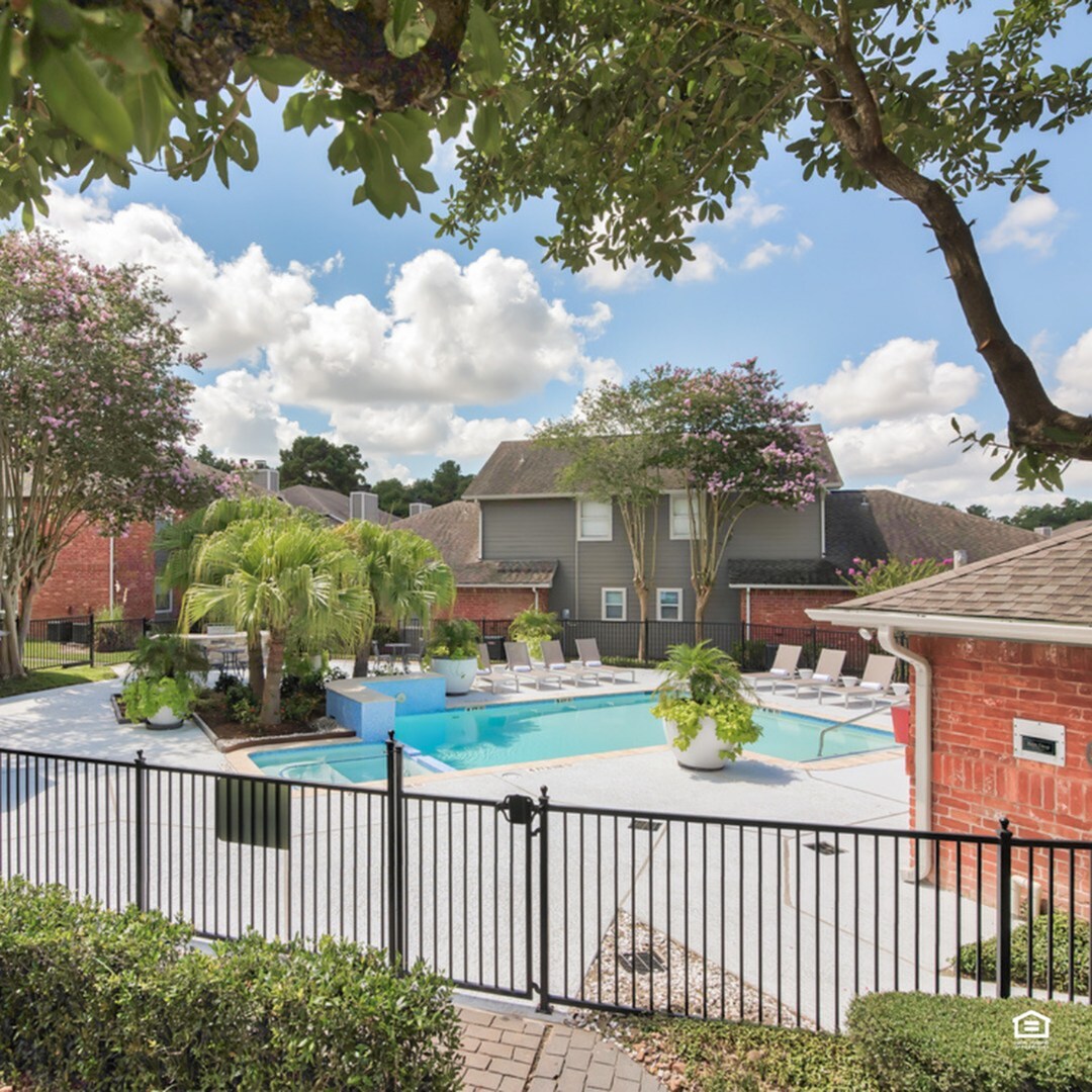 Charming outdoor pool area with lush greenery and comfortable lounge chairs, surrounded by neat landscaping and beautiful trees.