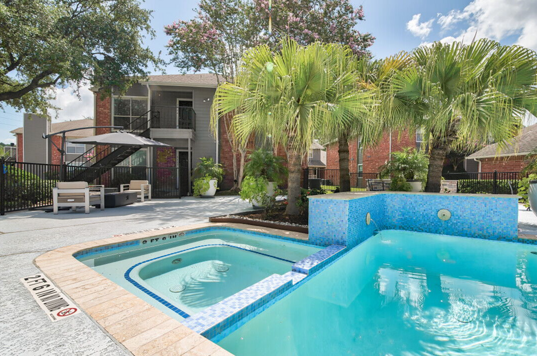 Charming apartment complex with a serene swimming pool, vibrant palm trees, and cozy outdoor seating area, ideal for relaxation.