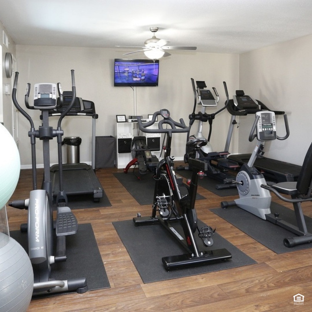 Modern fitness center featuring state-of-the-art exercise equipment, including treadmills, stationary bikes, and ellipticals on sleek wooden flooring.