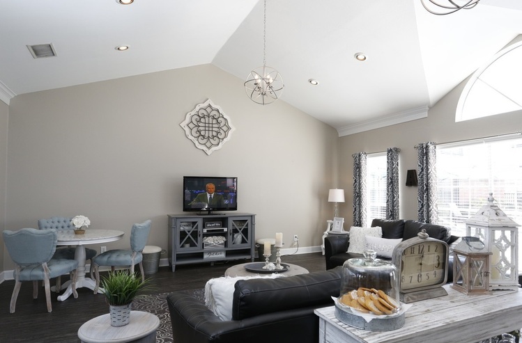 Elegant living room with vaulted ceiling, chic decor, and ample natural light, featuring a cozy seating area and contemporary accents.
