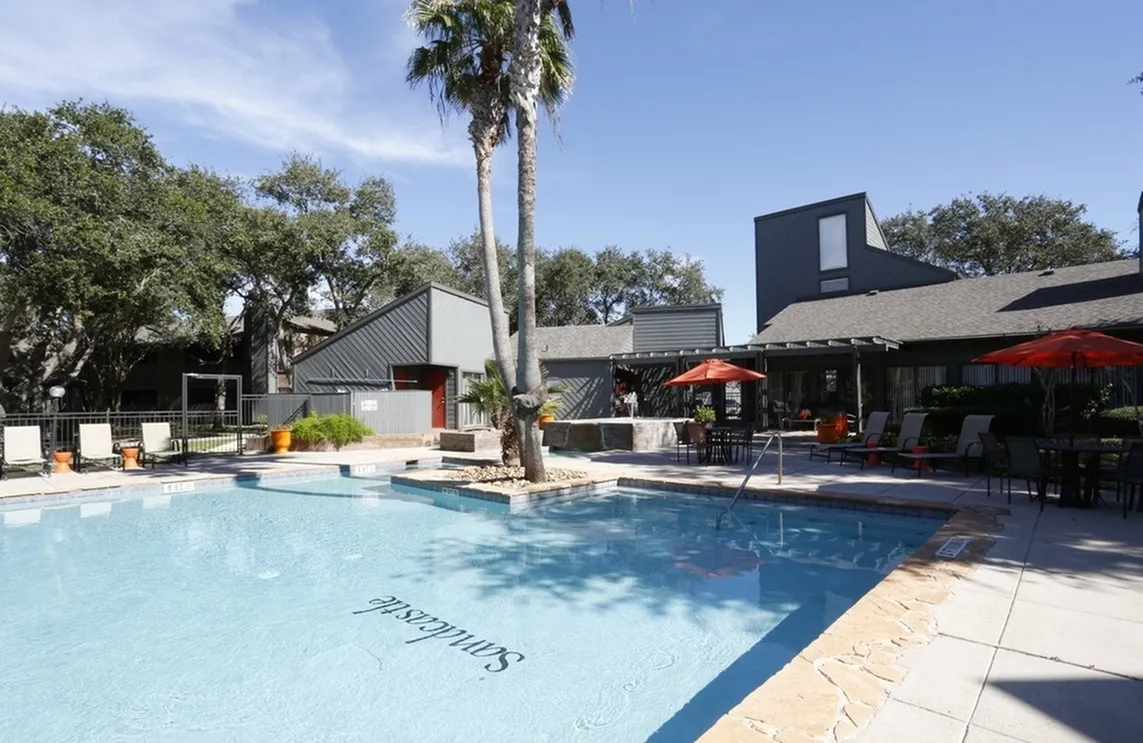 Inviting outdoor pool area with modern architecture, surrounded by lush trees and stylish lounge seating with vibrant umbrellas, perfect for relaxation and social gatherings.