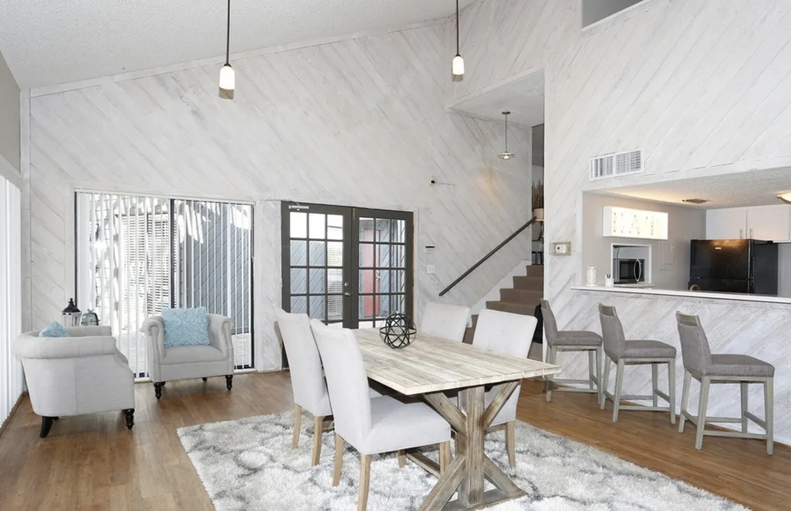 Elegant open-plan living and dining area with high ceilings, stylish accent walls, and modern kitchen bar stools.