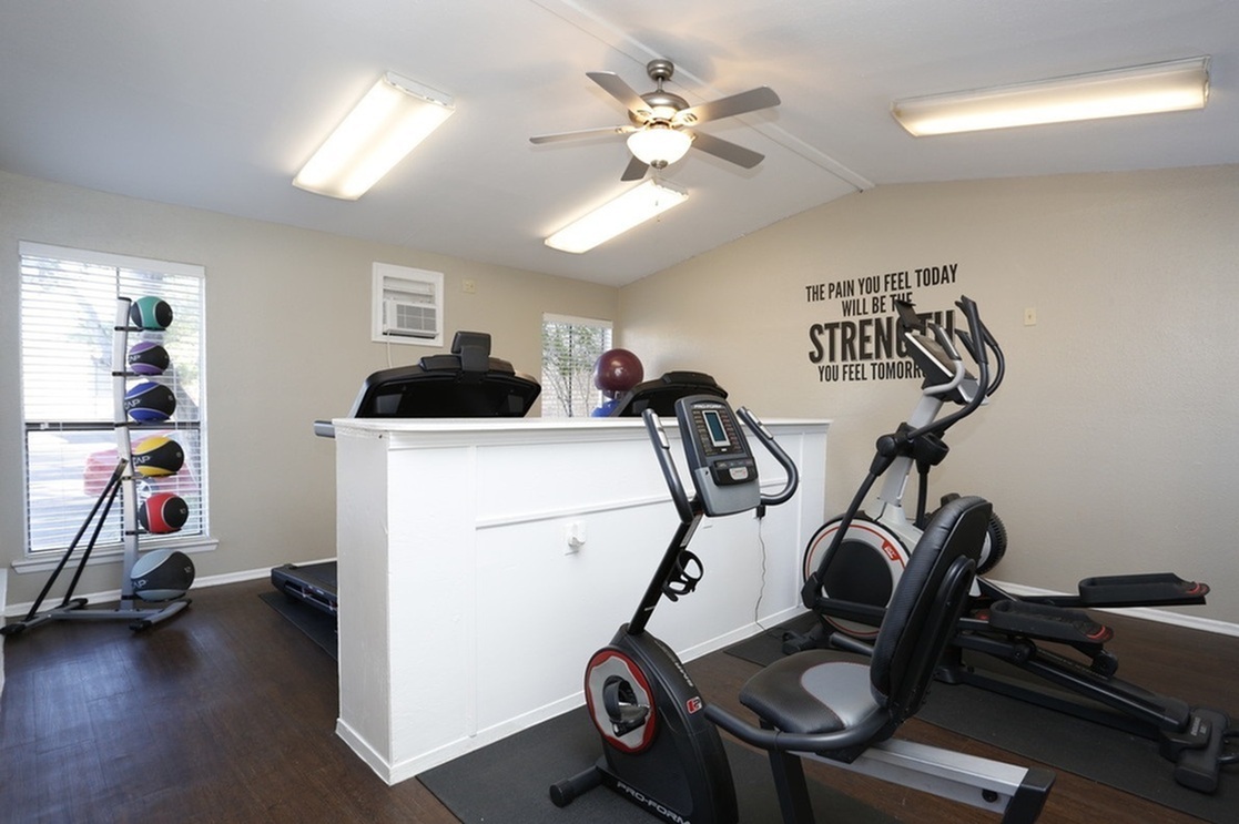 Modern fitness room with sleek exercise equipment, motivational wall quote, and bright, inviting atmosphere.