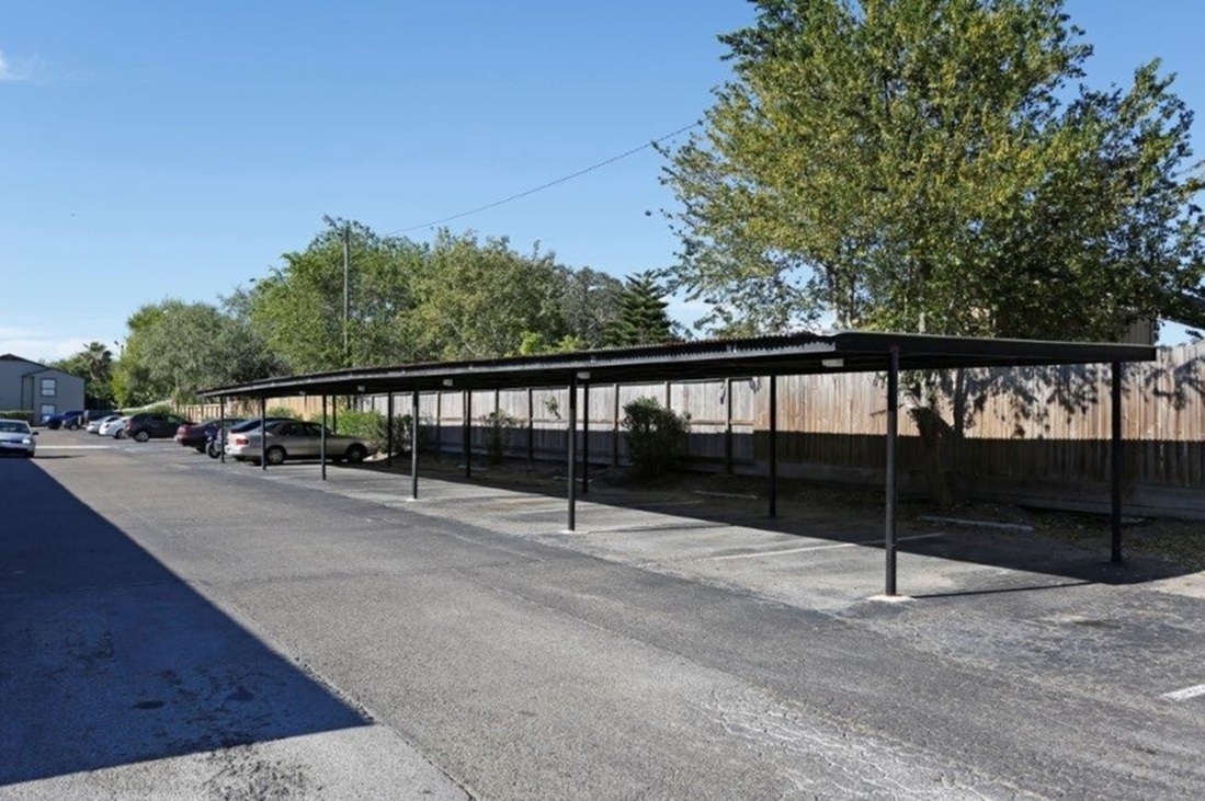 Spacious parking area with covered spaces and lush greenery, perfect for secure and convenient vehicle storage.