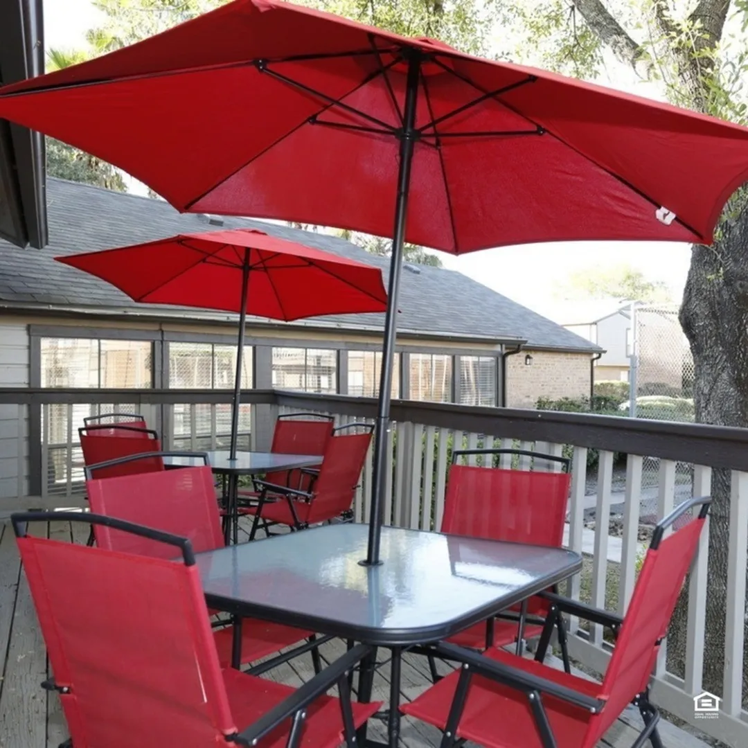 Charming outdoor patio with vibrant red umbrellas and cozy seating, perfect for relaxation and entertainment.