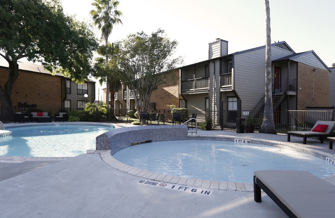 Inviting apartment complex with a sparkling swimming pool and lush greenery, perfect for relaxation and leisure.