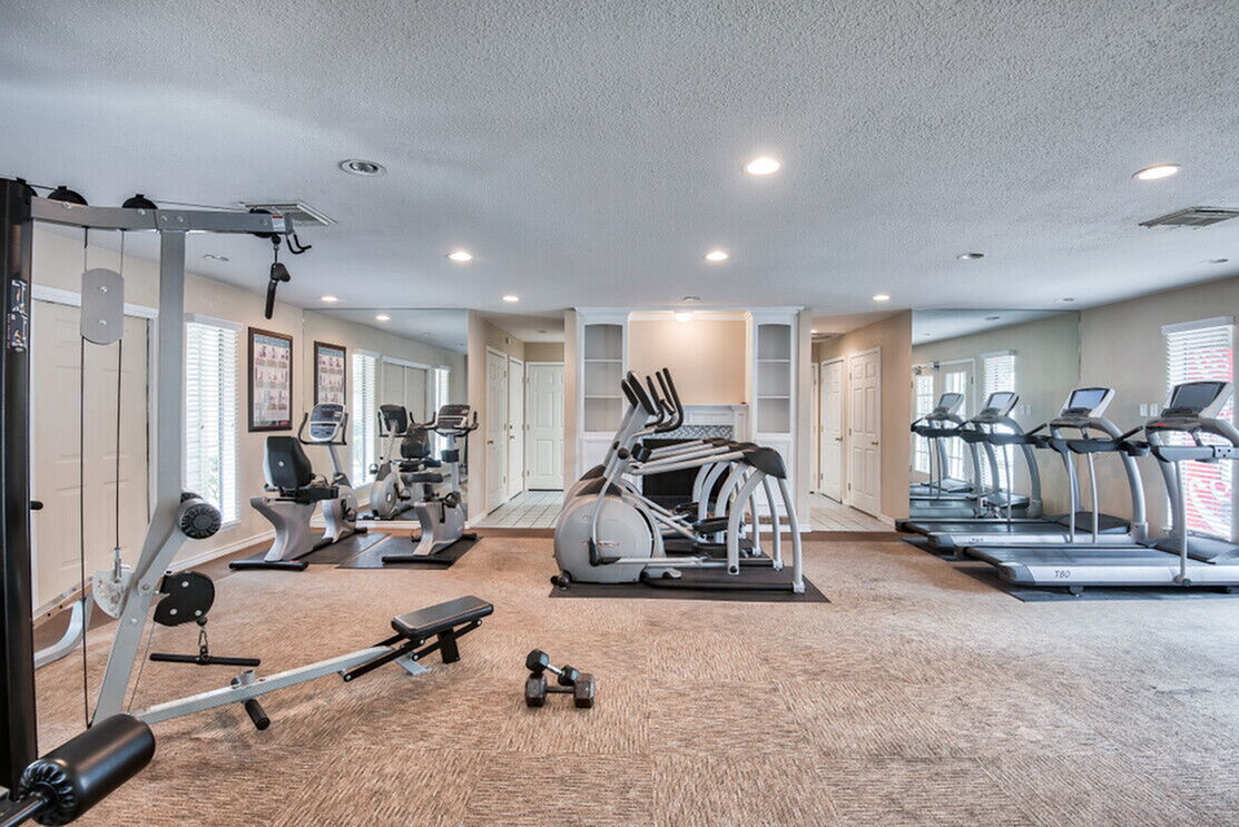 Modern fitness center with cardio machines, weight equipment, and large mirrors, offering a bright and inviting workout space.