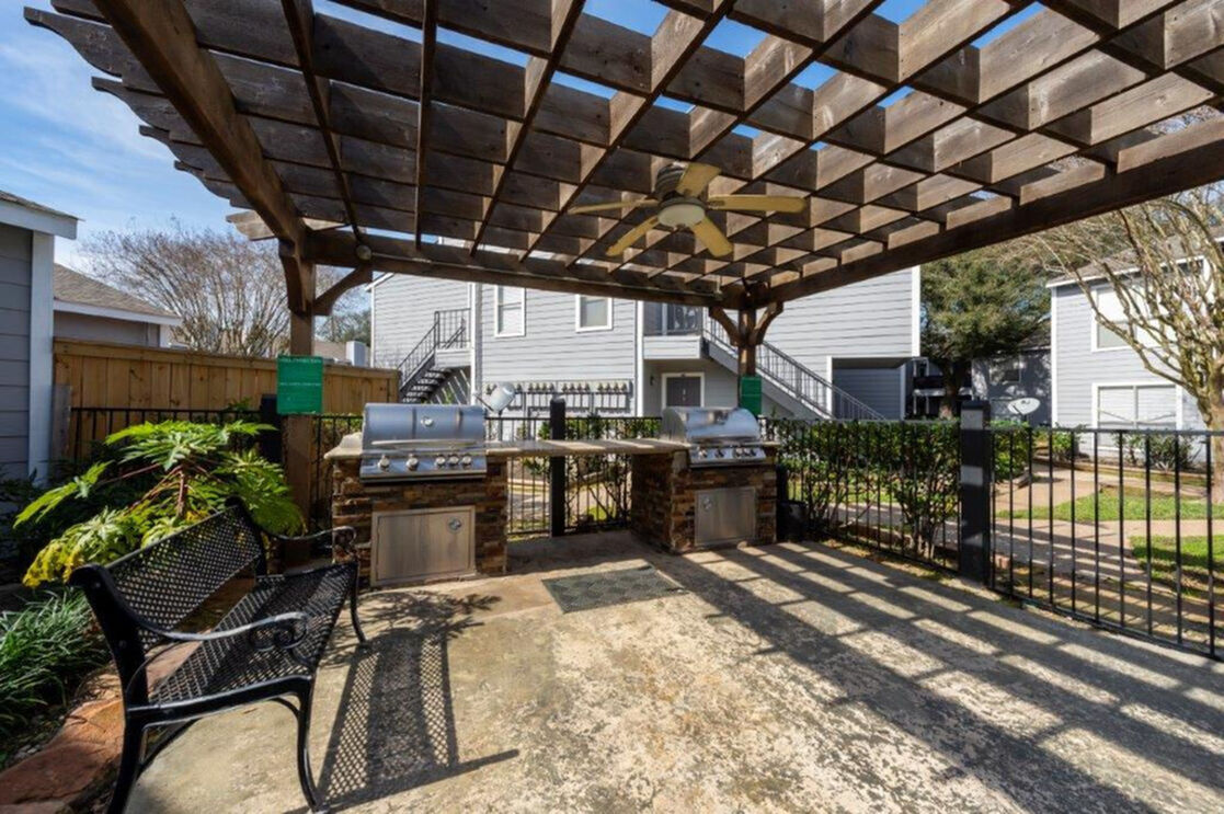 Charming outdoor barbecue area with modern grills and stylish pergola, perfect for entertaining in a serene apartment complex setting.