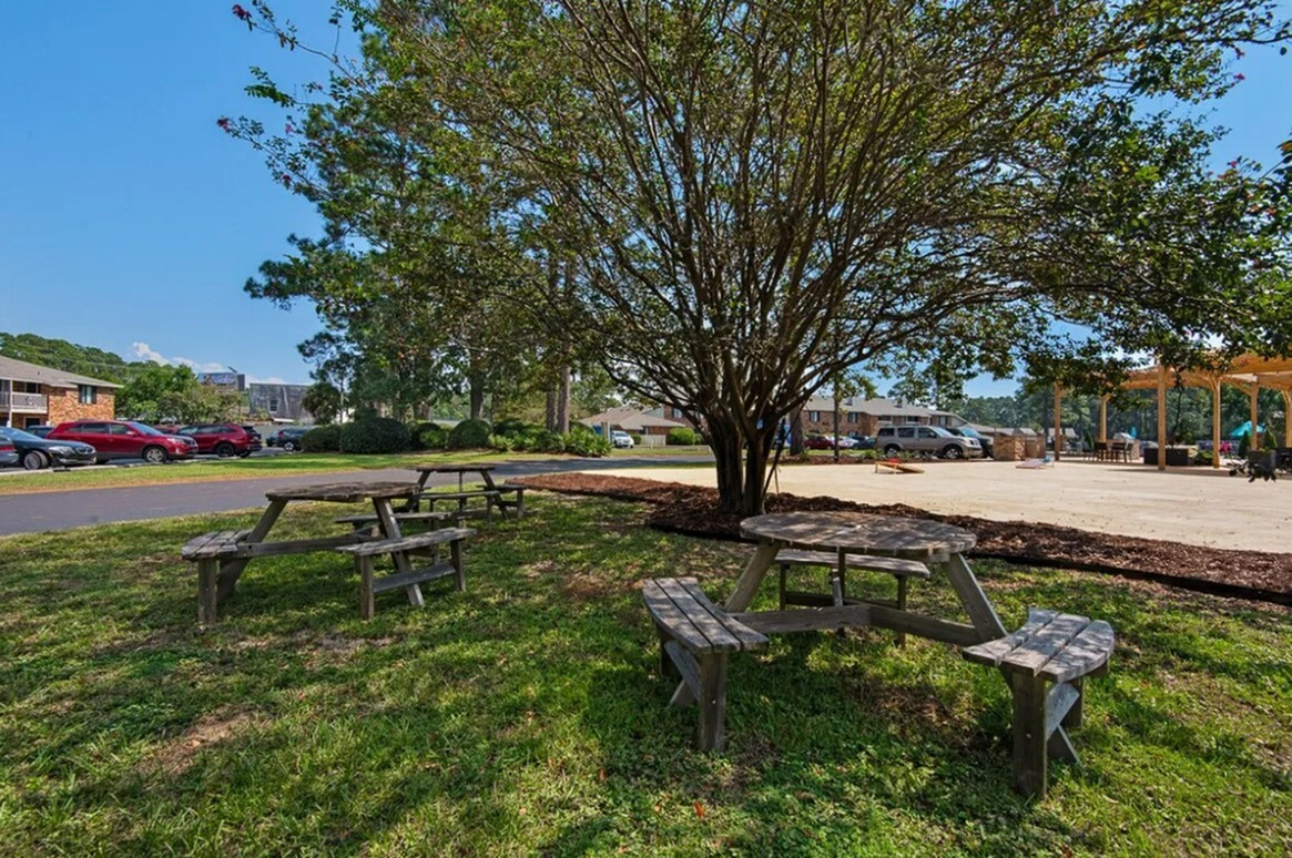 Inviting outdoor area with shaded picnic tables and lush greenery, ideal for relaxation and leisure.