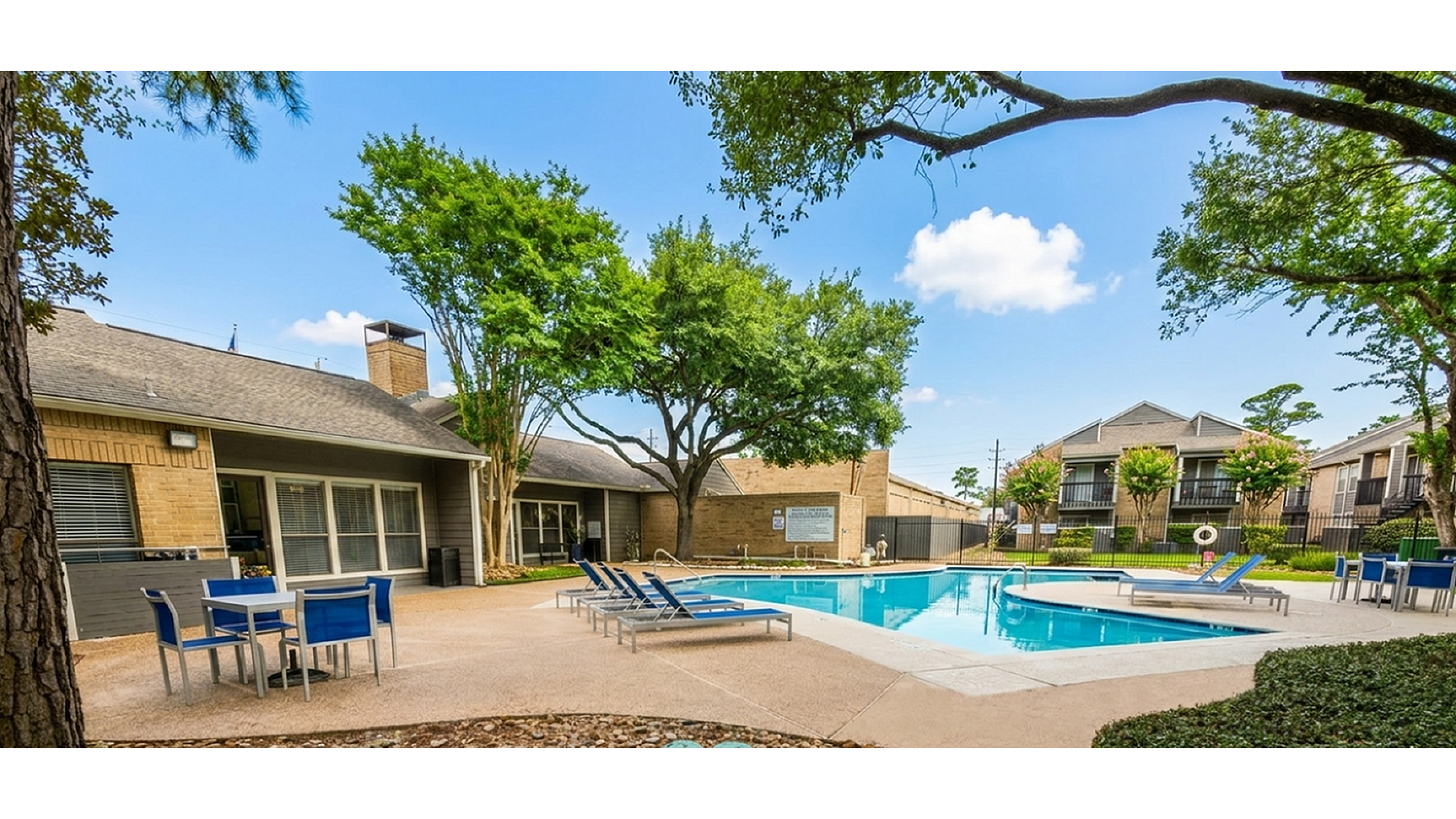 Inviting apartment community pool area with stylish lounge chairs and vibrant greenery, ideal for relaxing and socializing.