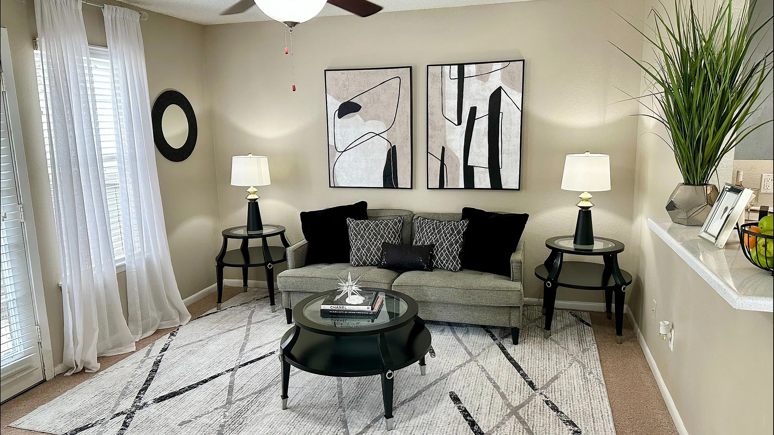 Inviting living room with elegant decor, featuring a cozy gray sofa, modern art pieces, and abundant natural light, perfect for relaxation.
