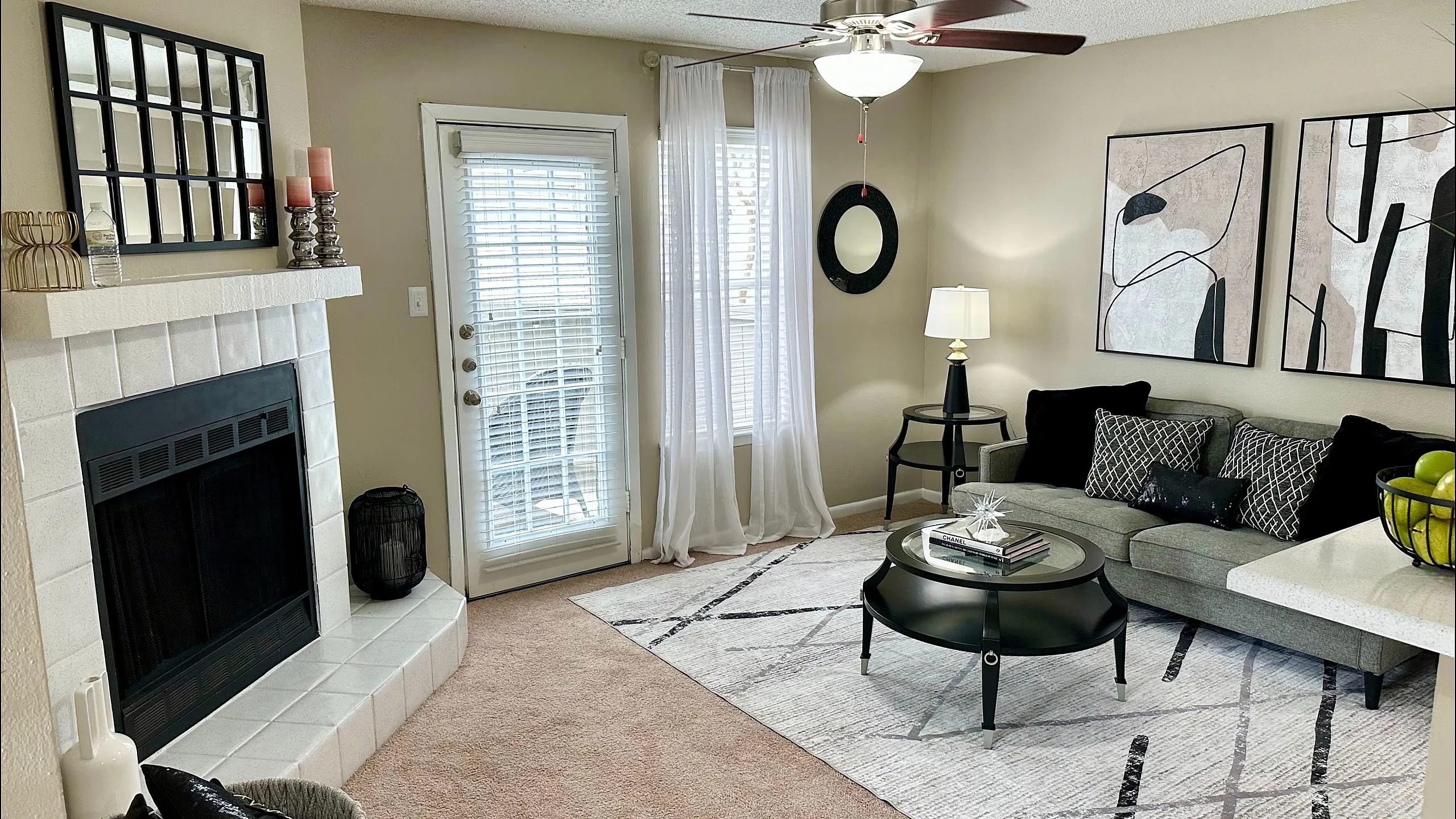 Chic living room showcasing a cozy sofa, modern abstract artwork, and stylish decor, featuring a warm fireplace and natural light from sliding glass doors.