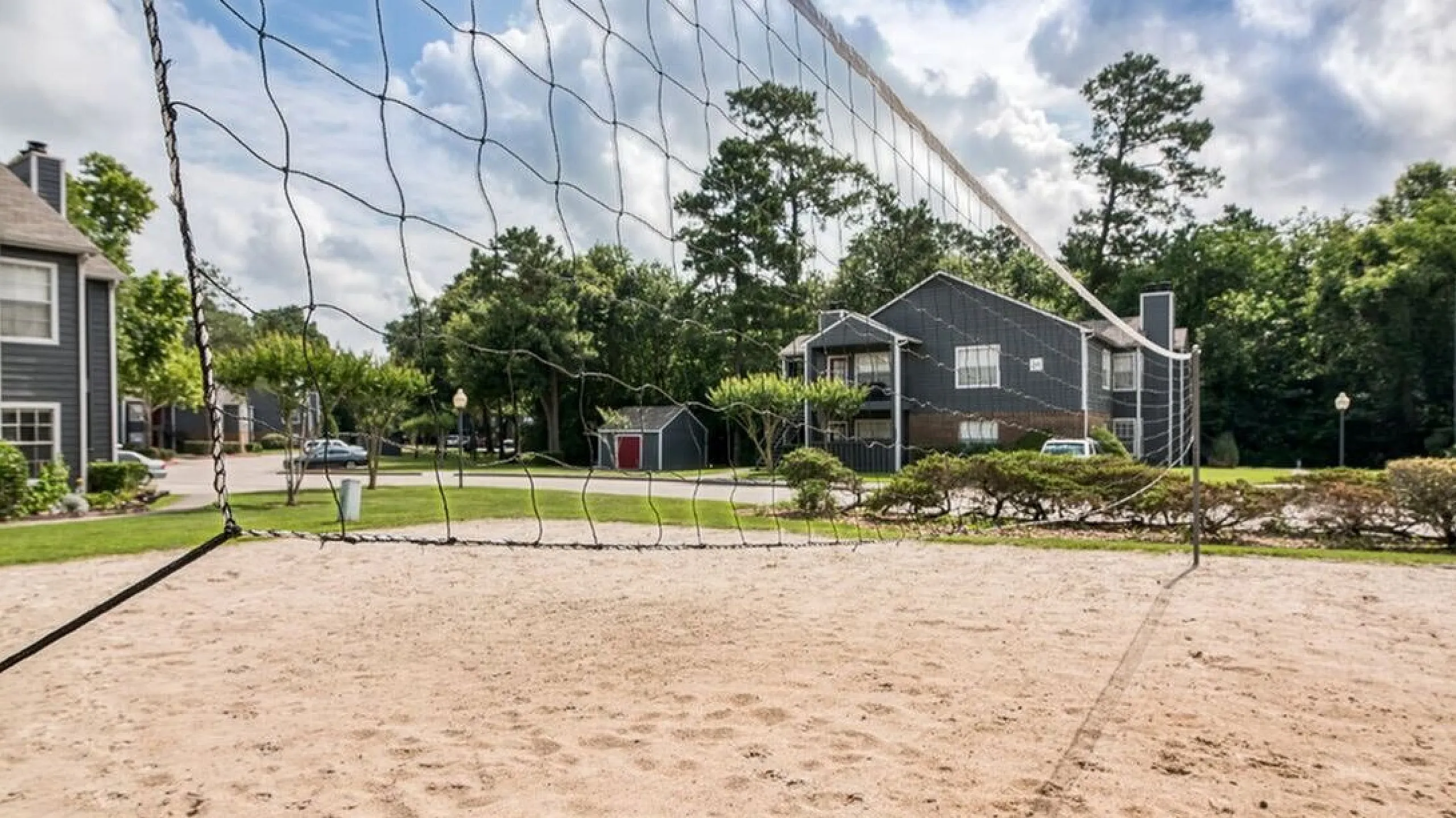 Inviting outdoor sand volleyball court surrounded by modern apartments and lush greenery, perfect for active living.