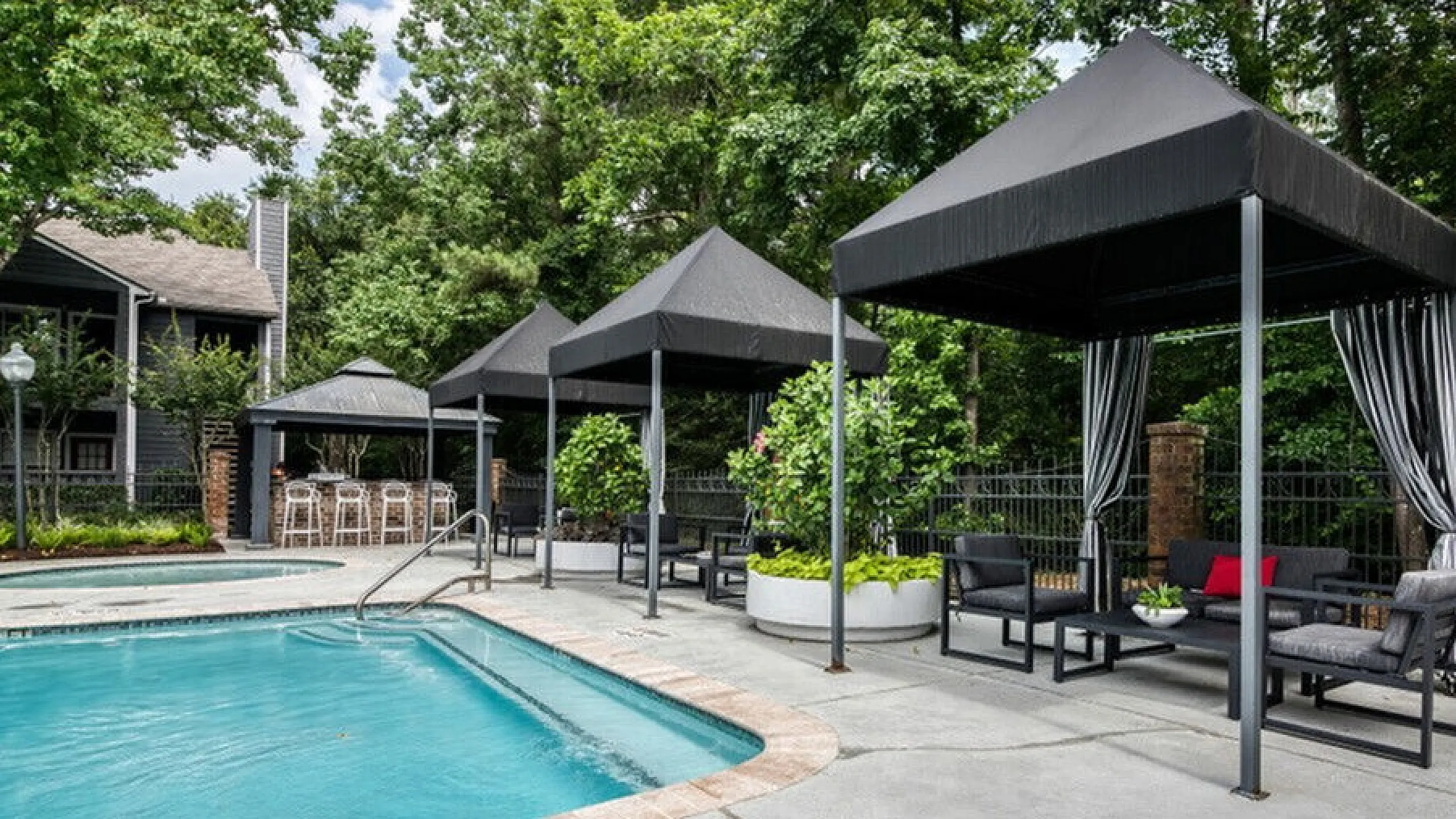 Elegant outdoor pool area with modern cabanas and lush greenery, perfect for relaxation and socializing.