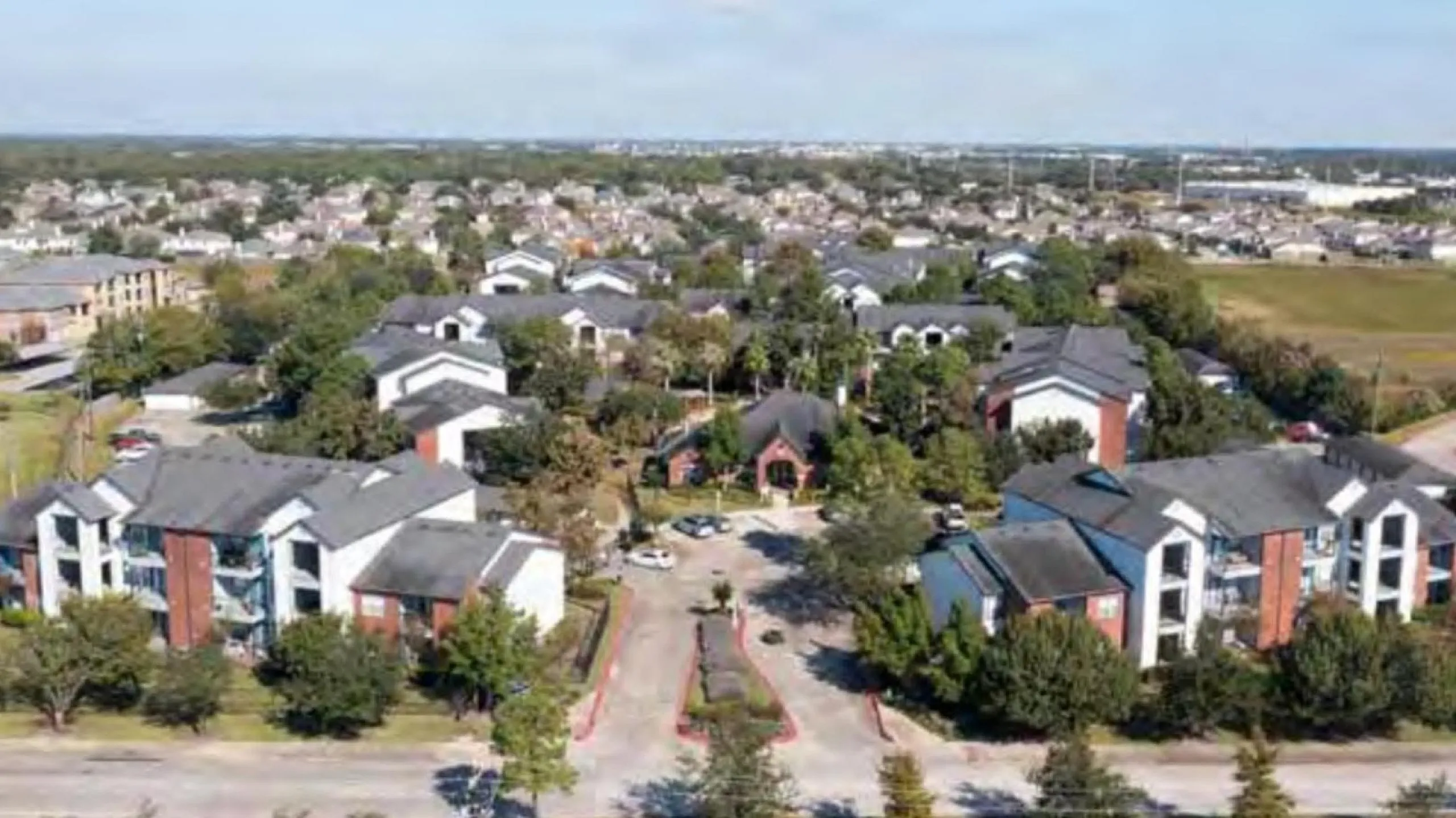 Charming aerial view of a vibrant apartment community surrounded by lush greenery, offering spacious living in a serene neighborhood.