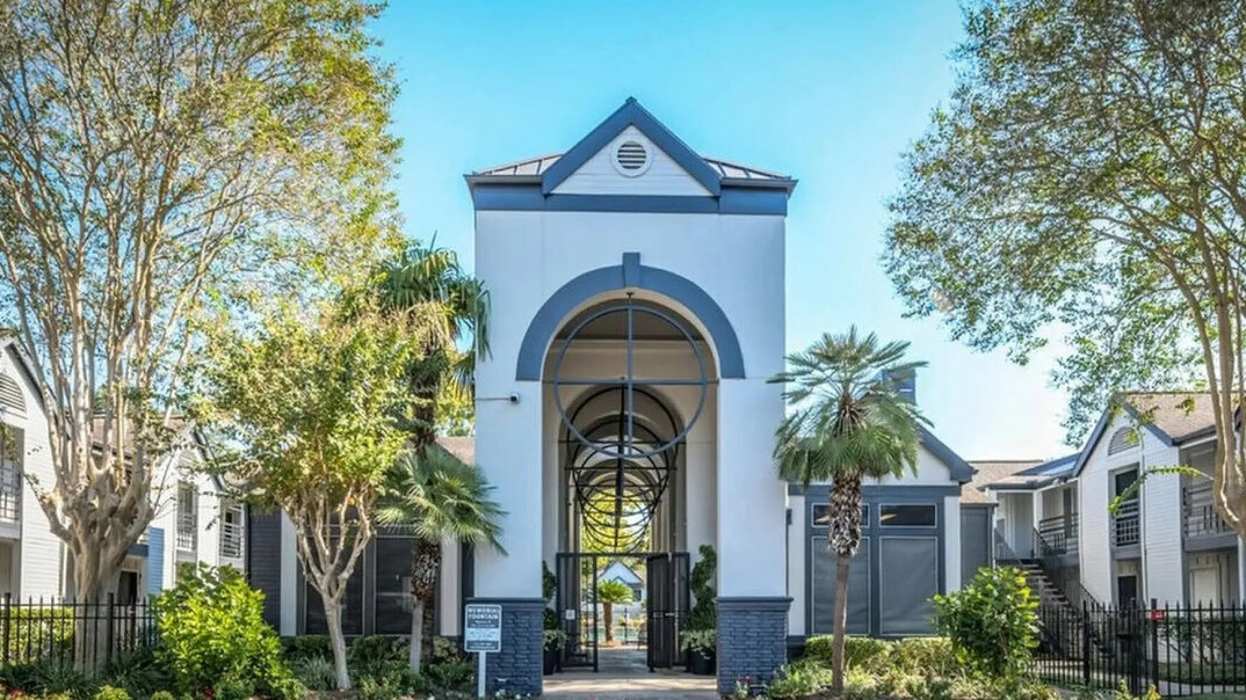 Elegant apartment entrance with modern architecture, lush greenery, and inviting pathways.