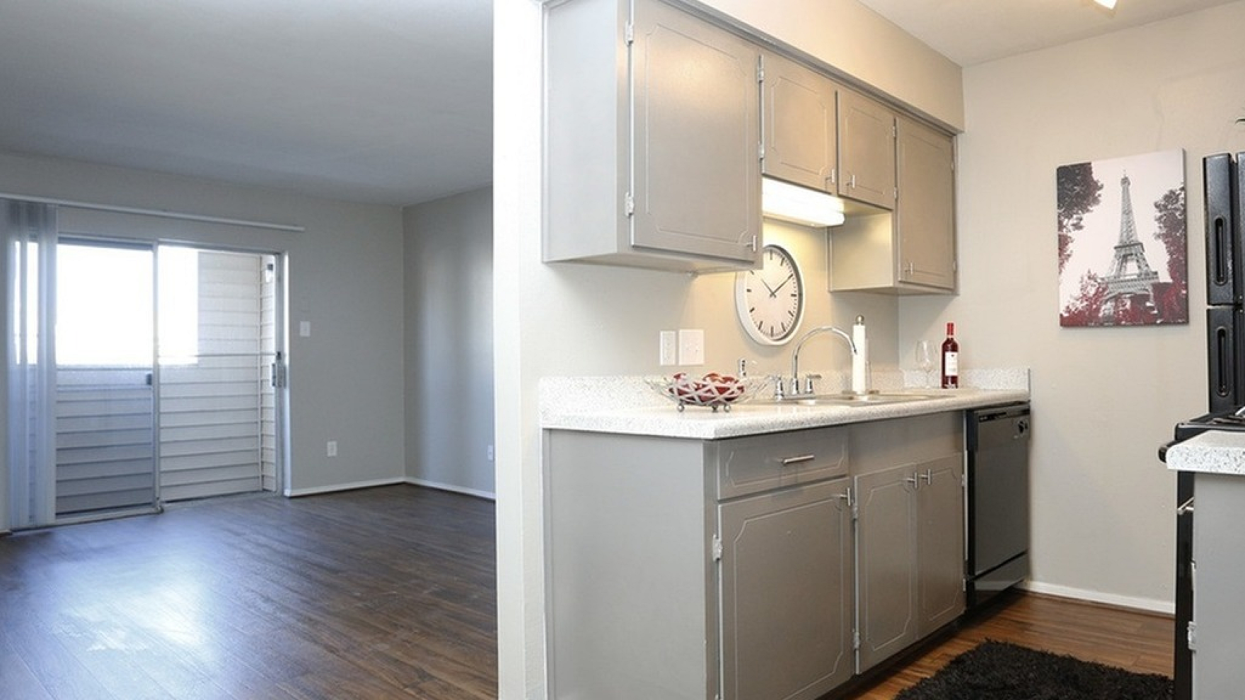 Modern open-concept kitchen and living area featuring sleek gray cabinetry, hardwood floors, and ample natural light through sliding glass doors.