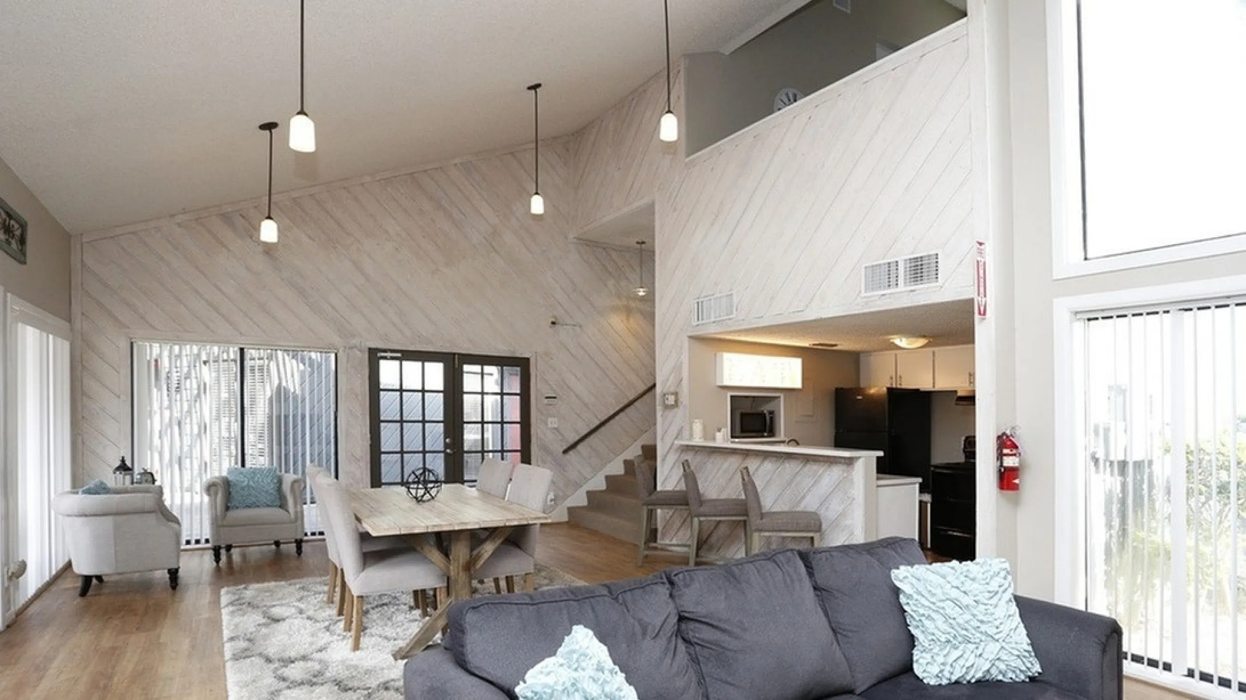 Spacious open-plan living area with modern decor, high ceilings, and abundant natural light. Features a cozy sitting area, elegant dining space, and a sleek kitchen island.