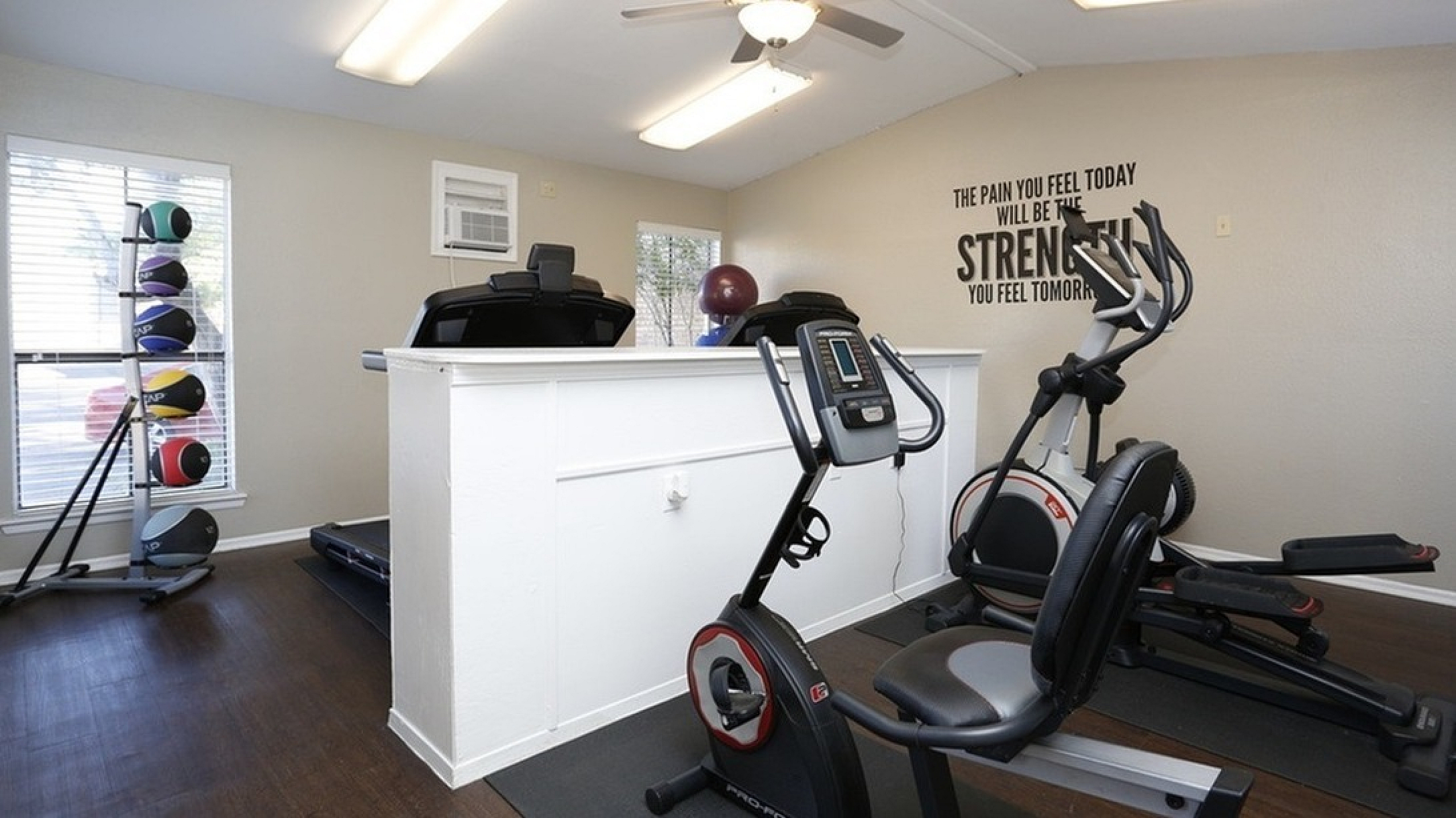 Inviting fitness room with modern exercise equipment and motivational wall quote, perfect for an energizing workout.