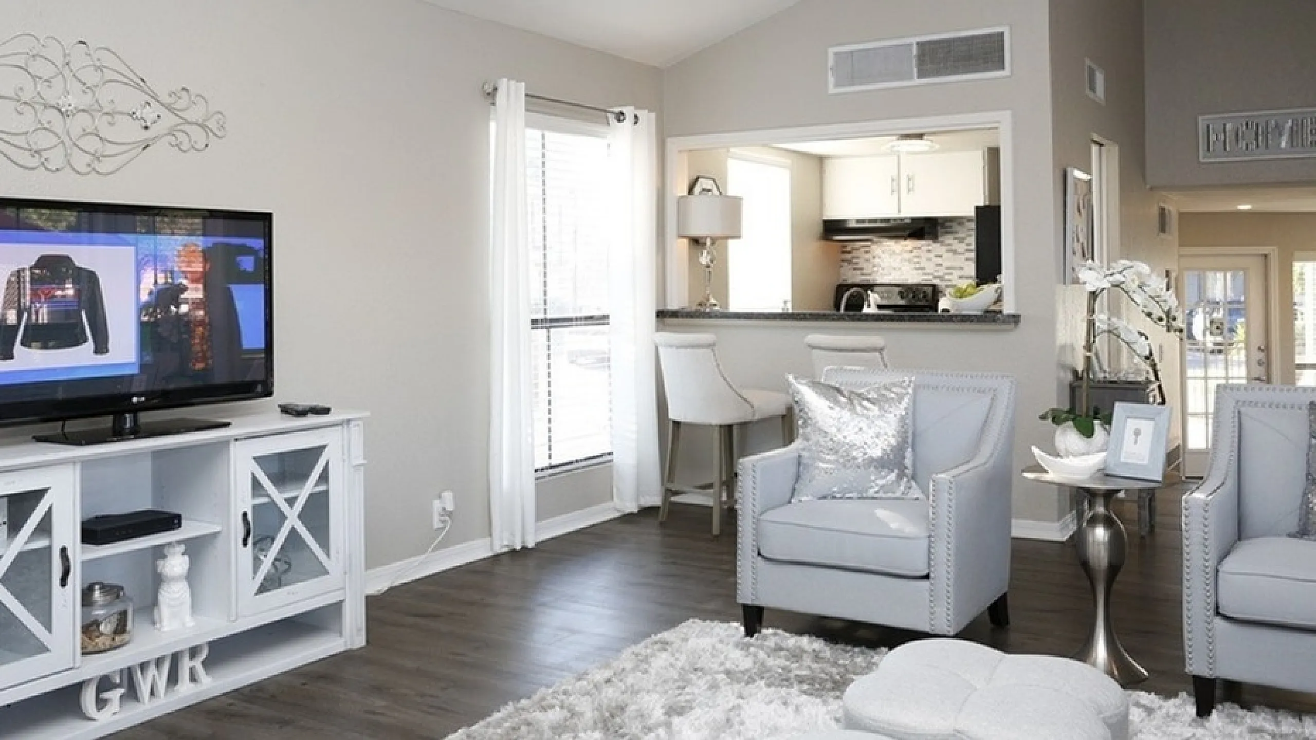 Bright and elegant living room with chic decor, featuring a modern open-concept kitchen and stylish furnishing.