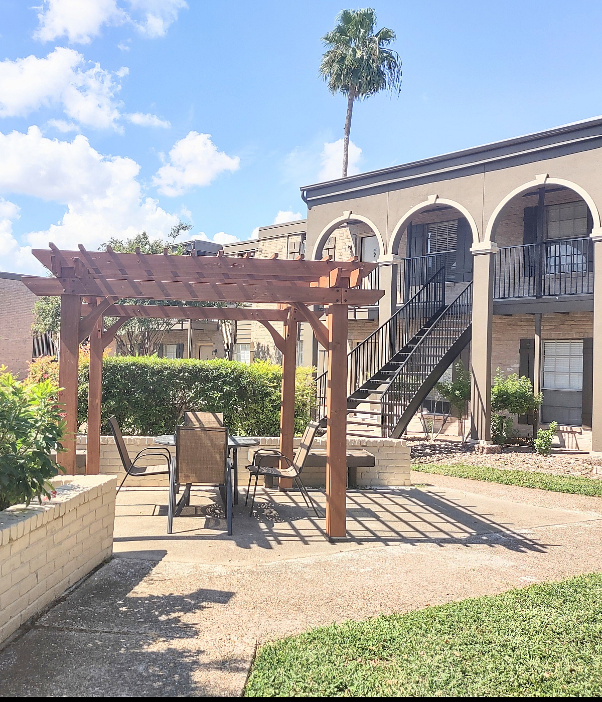 Charming outdoor courtyard with pergola-shaded seating and vibrant landscaping in a modern apartment complex.