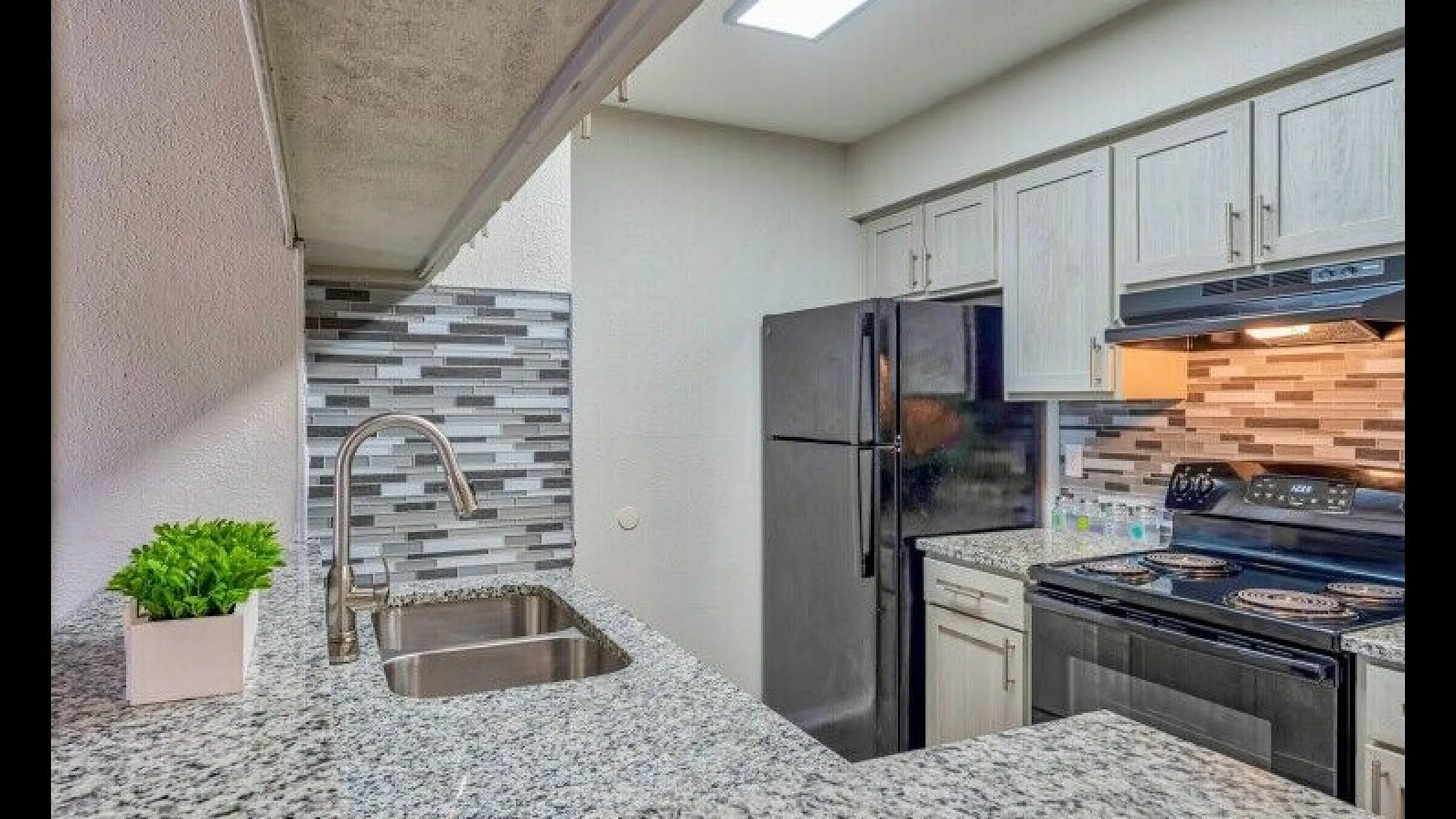 Modern kitchen with sleek granite countertops, stainless steel sink, and stylish backsplash.