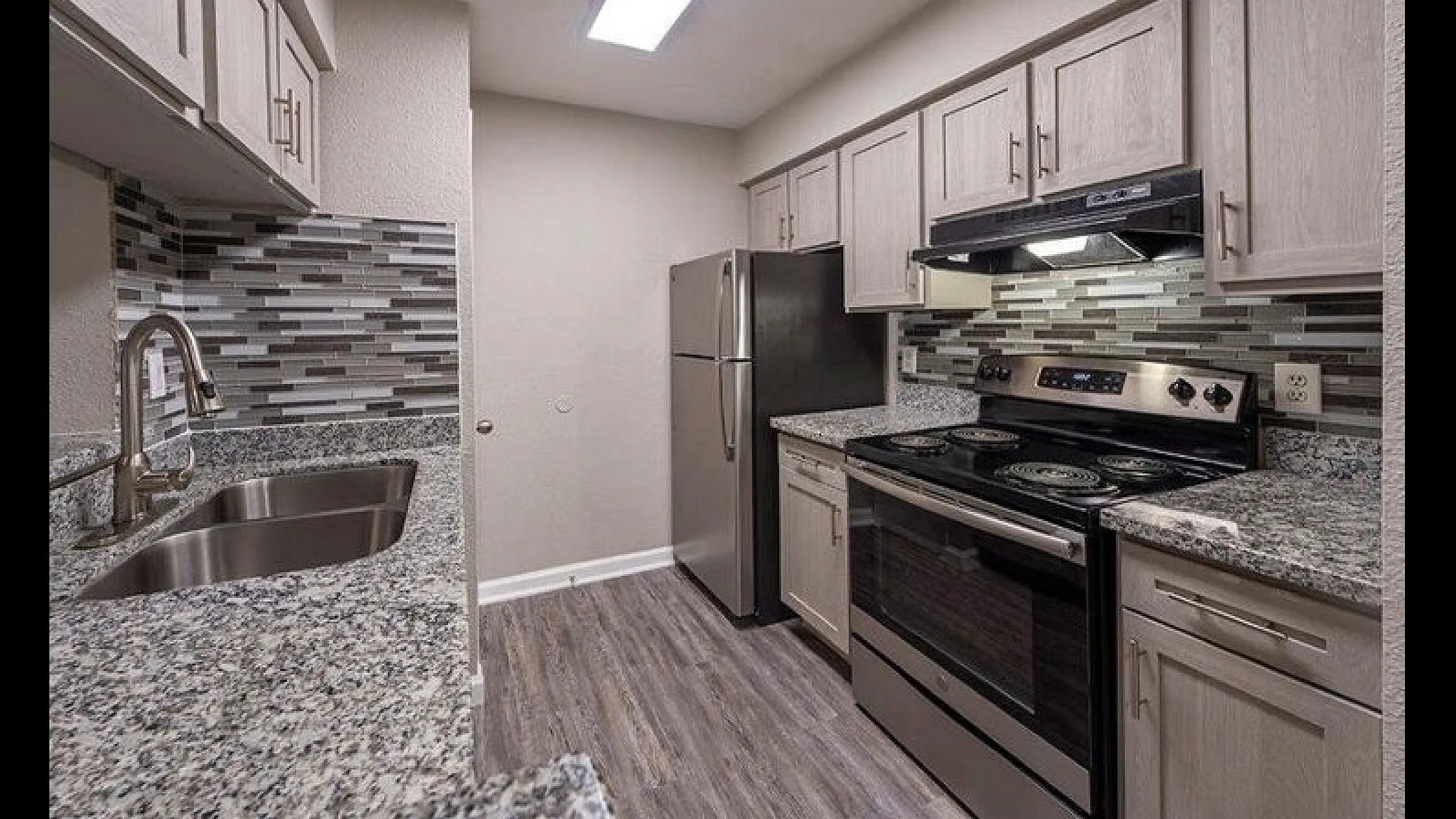 Modern kitchen with sleek granite countertops, stainless steel appliances, and stylish backsplash for a contemporary living experience.