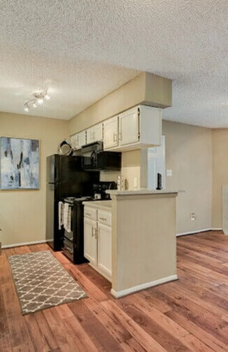 Modern open-plan kitchen and living area with stylish wood flooring, cozy fireplace, and natural light from sliding glass doors.