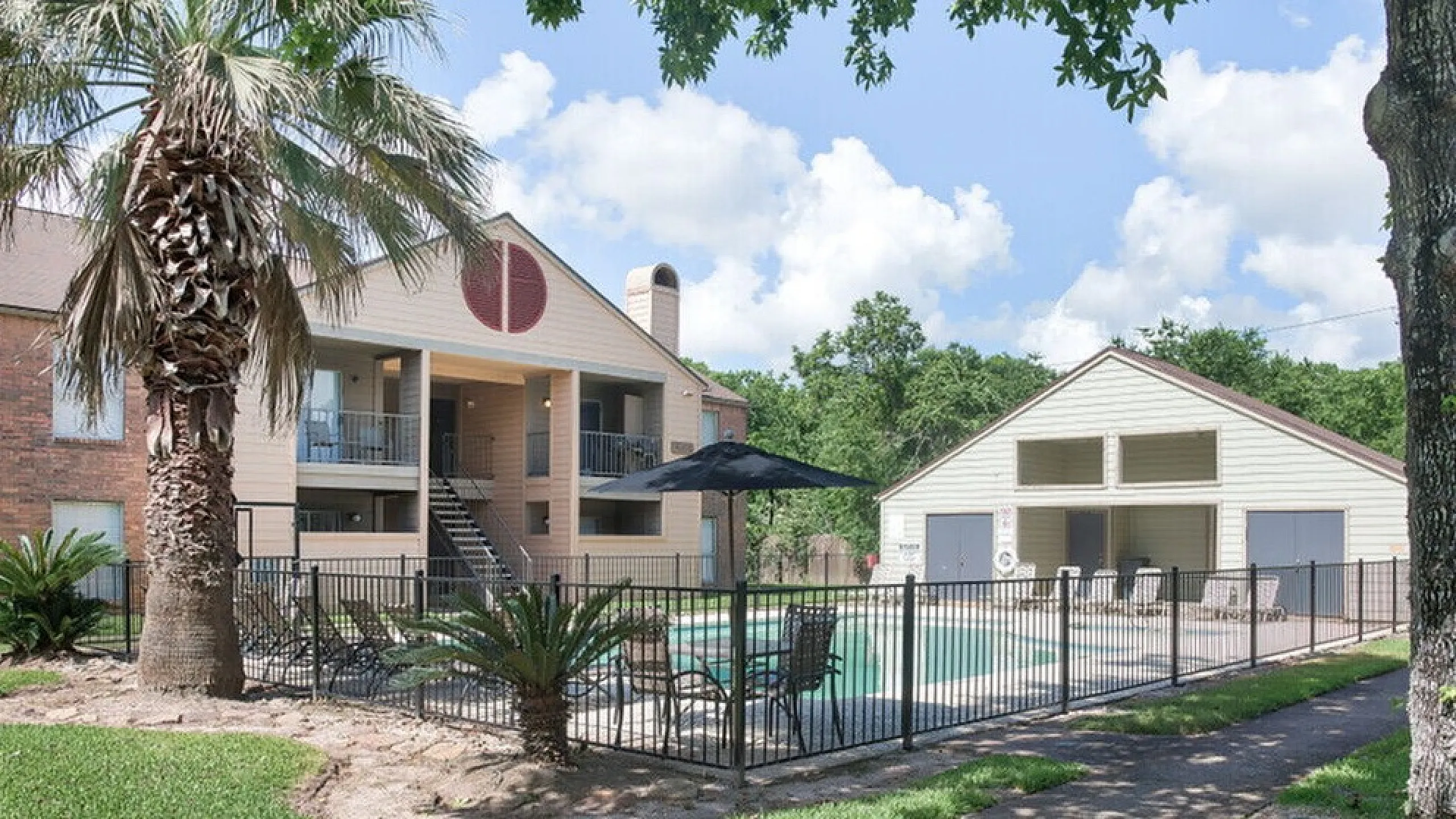 Charming residential complex with a refreshing pool surrounded by lush greenery, palm trees, and modern amenities, perfect for relaxation and community living.