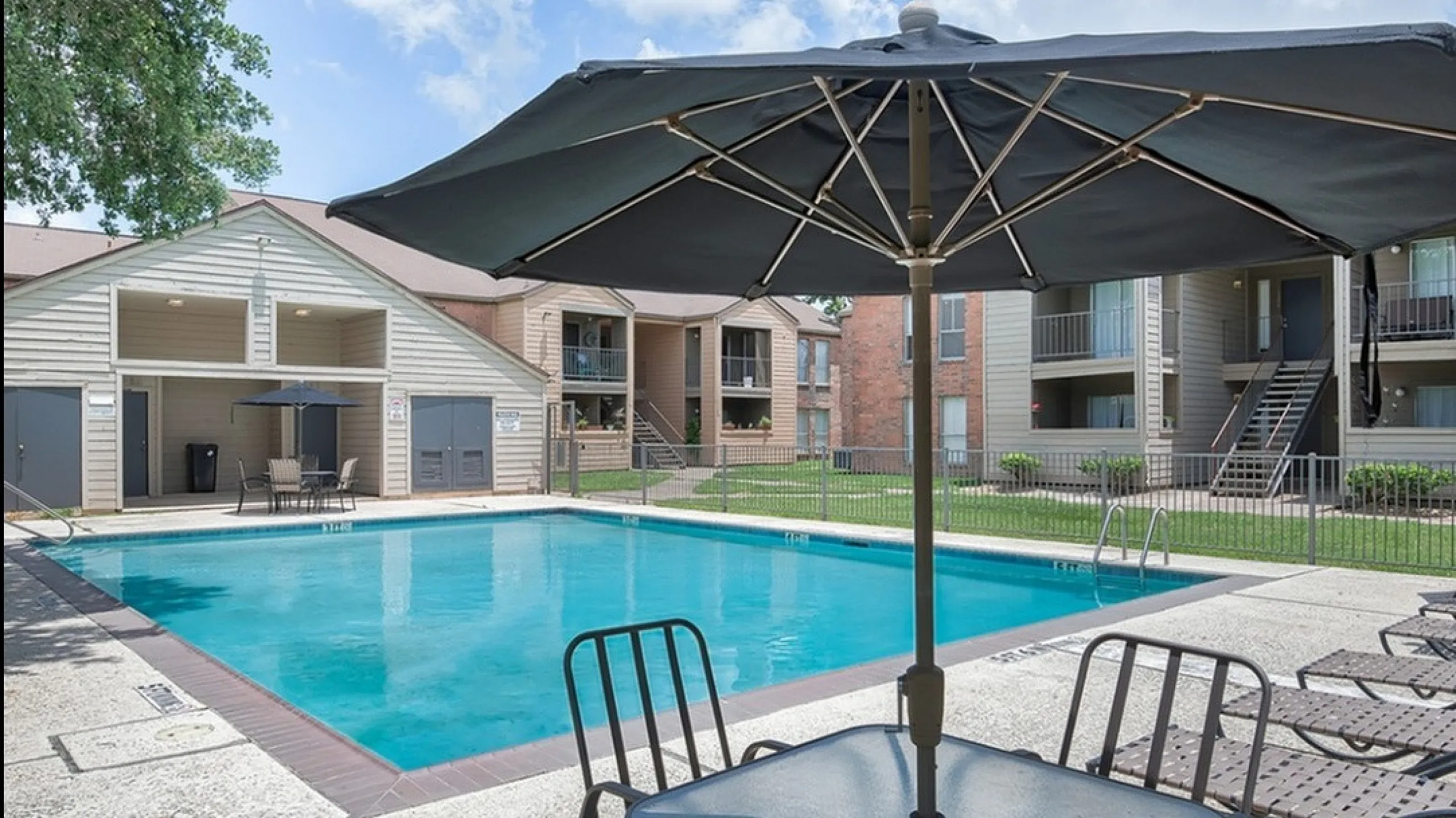Inviting apartment complex pool area with sun loungers and shaded seating, perfect for relaxation and leisure.