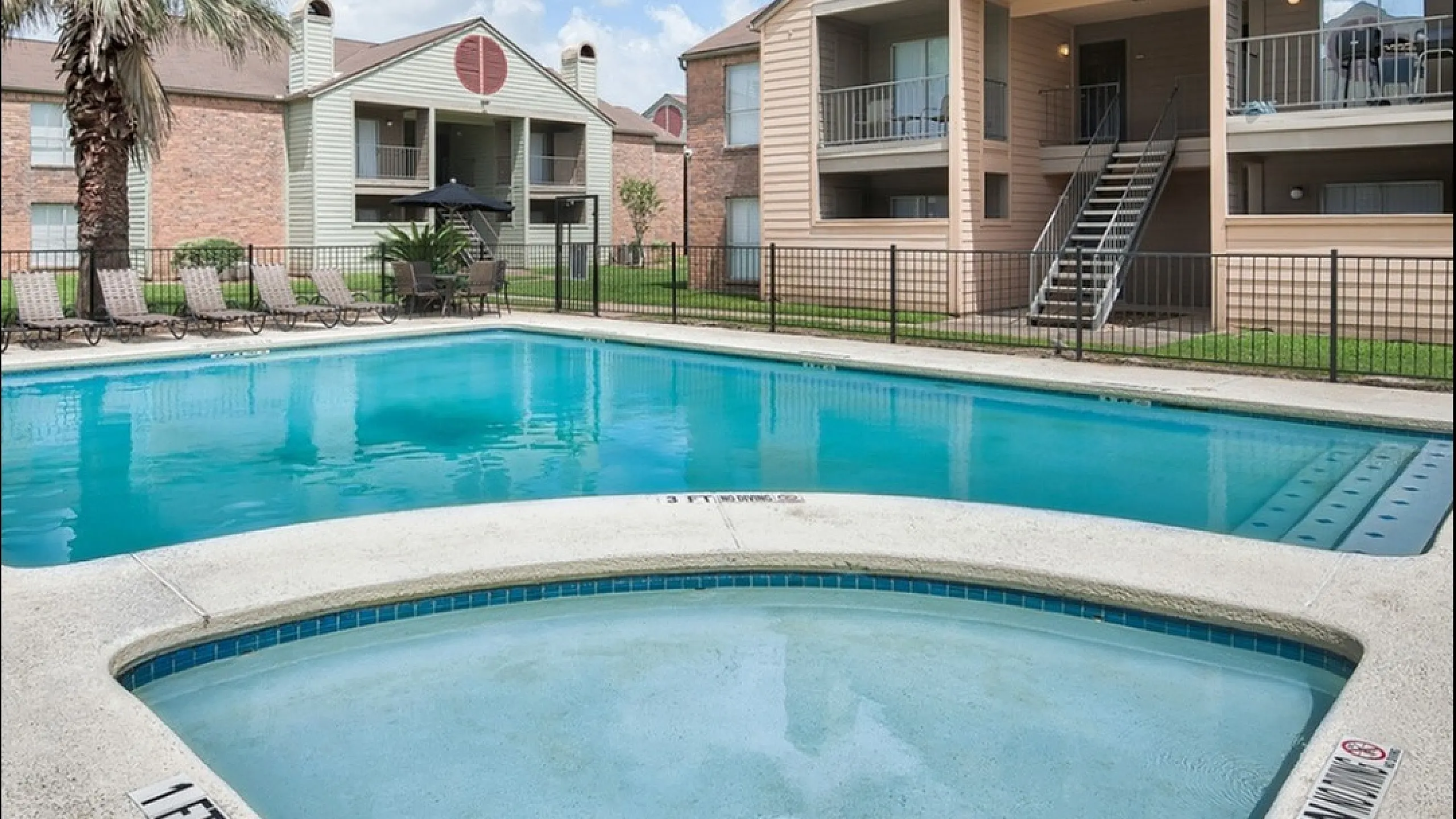 Inviting apartment complex with balconies overlooking a serene swimming pool and palm trees, perfect for relaxation and leisure.