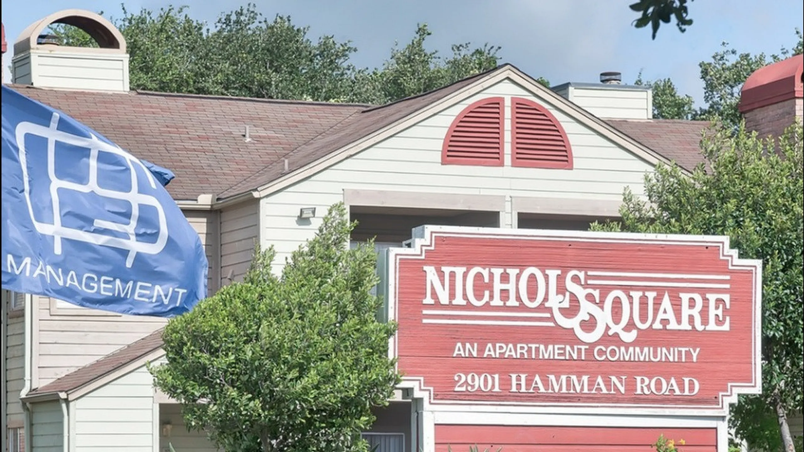 Charming apartment community with welcoming signage and lush landscaping at Nichols Square, 2901 Hamman Road.