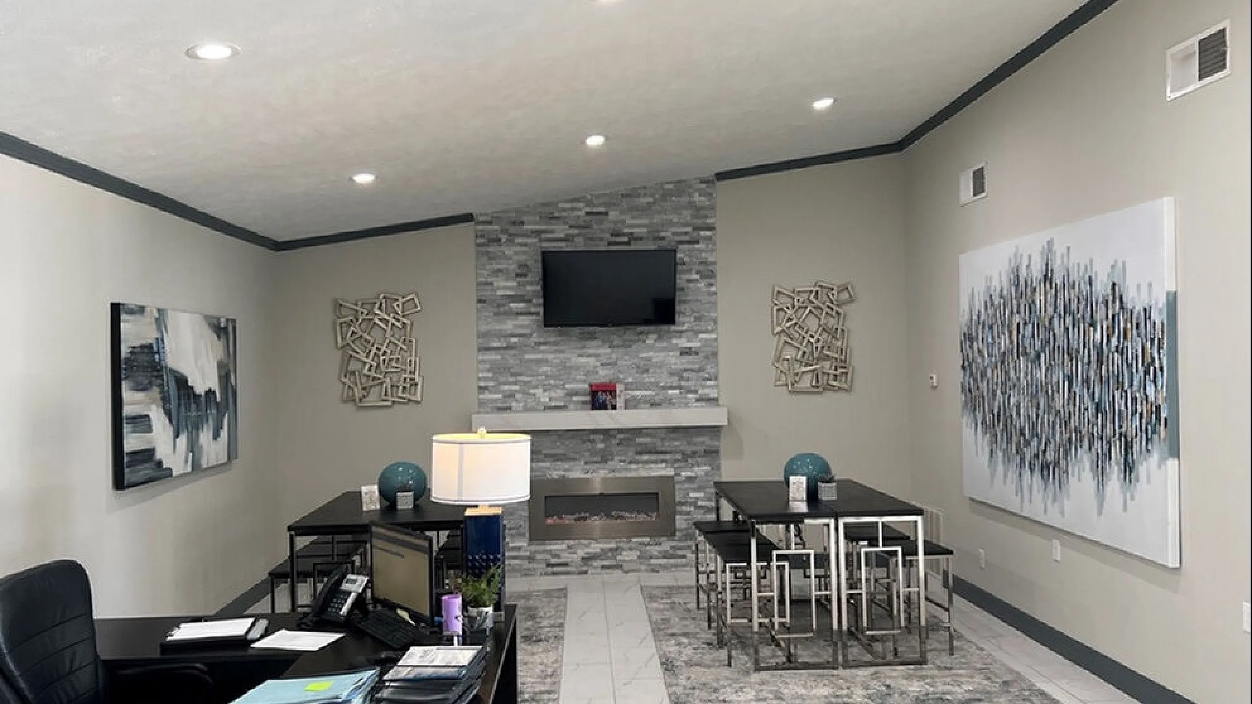 Modern office space with sleek design, stone accent wall, contemporary artwork, and ambient lighting for a professional atmosphere.
