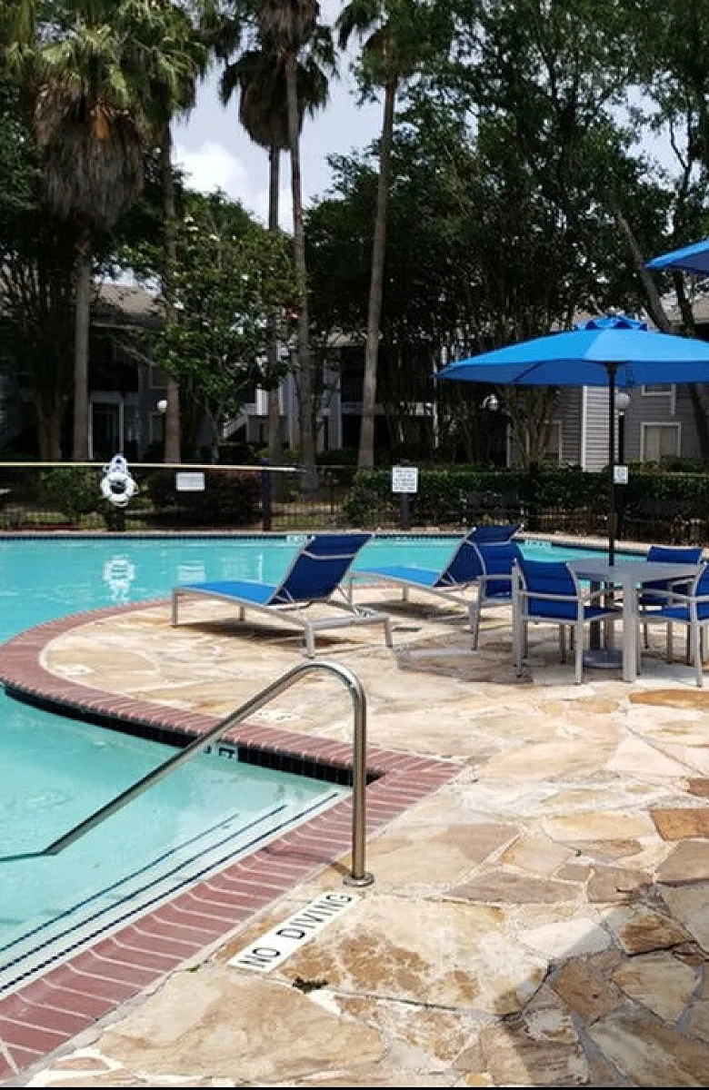 Inviting outdoor pool area with stylish lounge chairs and vibrant blue umbrellas, perfect for relaxation under the sun.