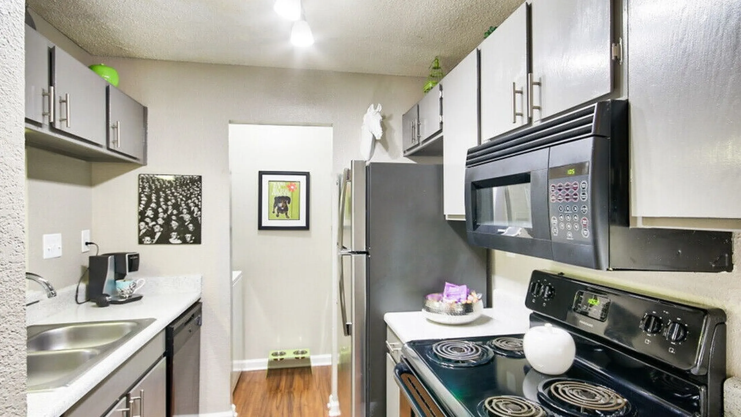 Modern kitchen with elegant cabinetry, sleek countertops, stainless steel appliances, and warm wood flooring.