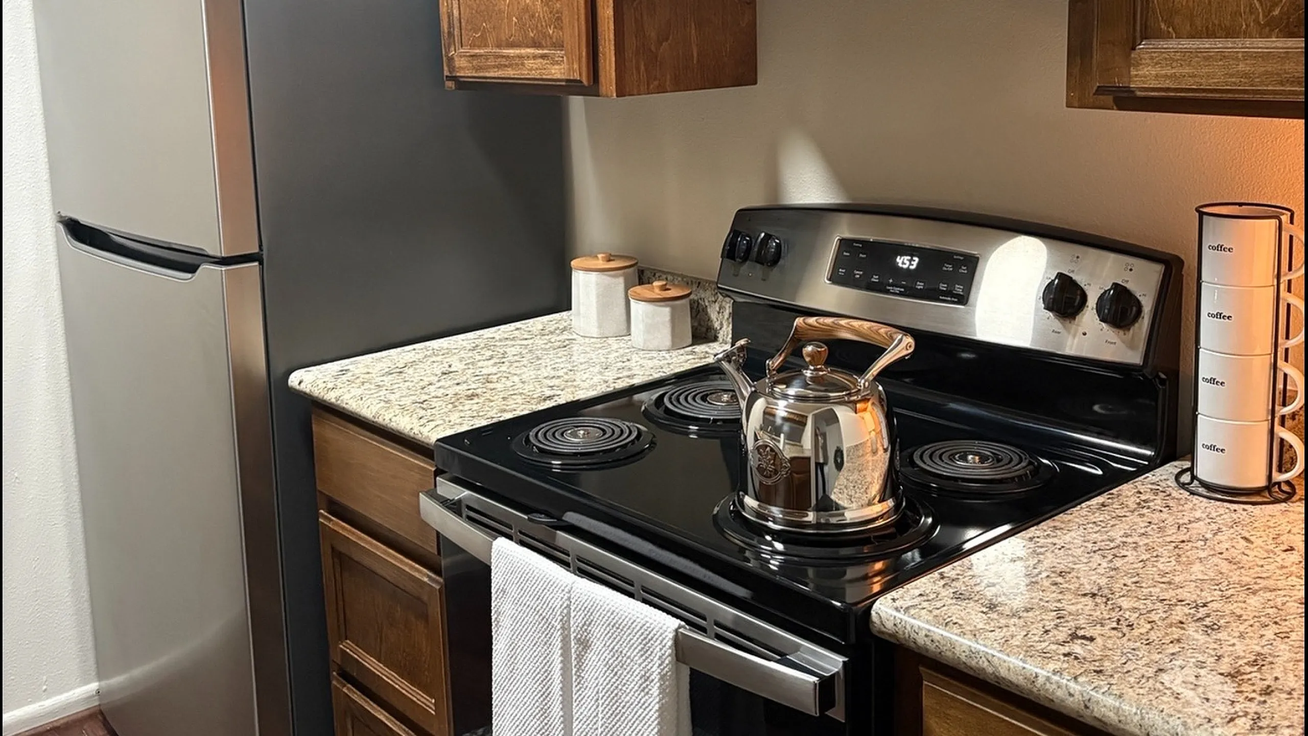 Modern kitchen with stainless steel appliances, granite countertops, and sleek wooden cabinetry.