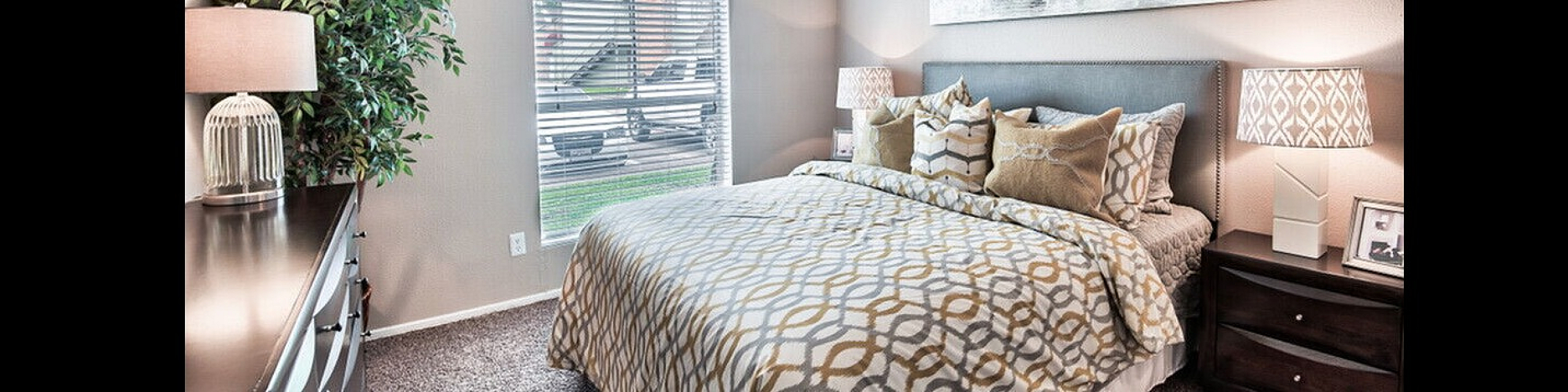 Cozy bedroom with stylish decor featuring a comfortable bed, charming bedside lamps, and a large window allowing natural light.