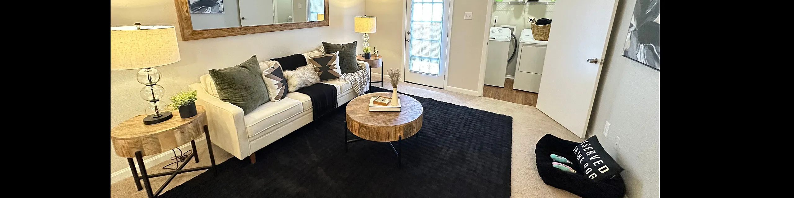 Cozy living room with elegant decor, featuring a plush sofa, stylish coffee table, and warm lighting. Adjacent laundry area adds convenience.