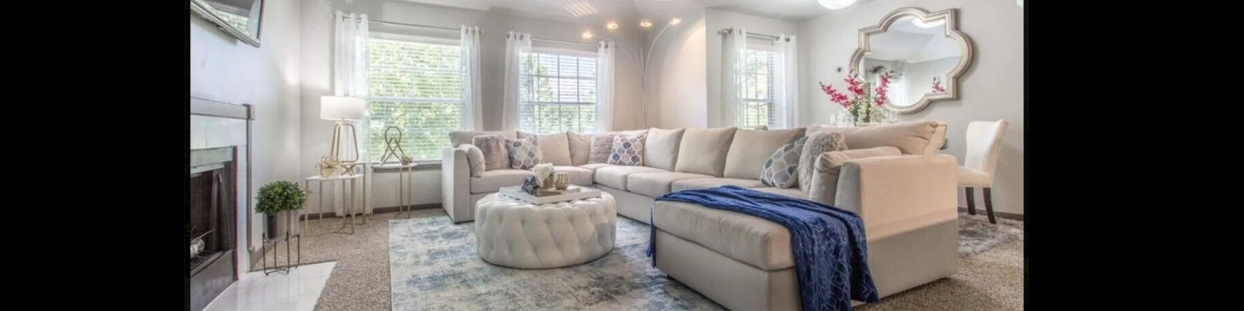 Inviting living room with a plush L-shaped sofa, elegant decor, and abundant natural light from large windows.