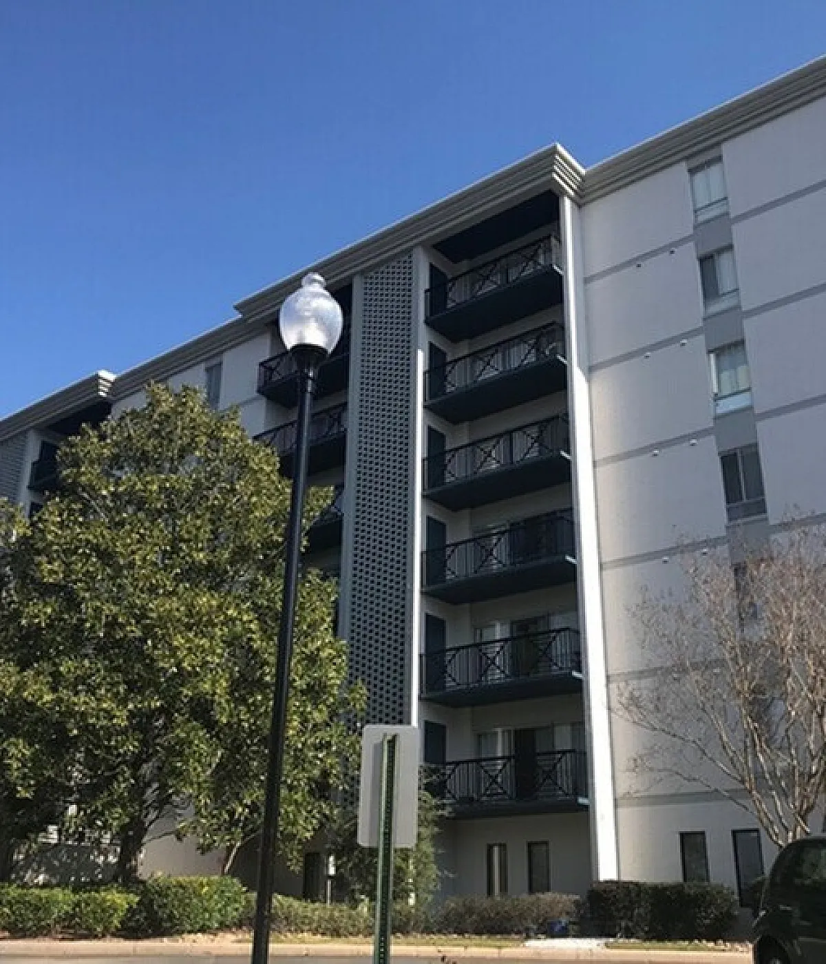 Modern apartment building with stylish balconies, large windows, and lush landscaping in a serene urban setting.