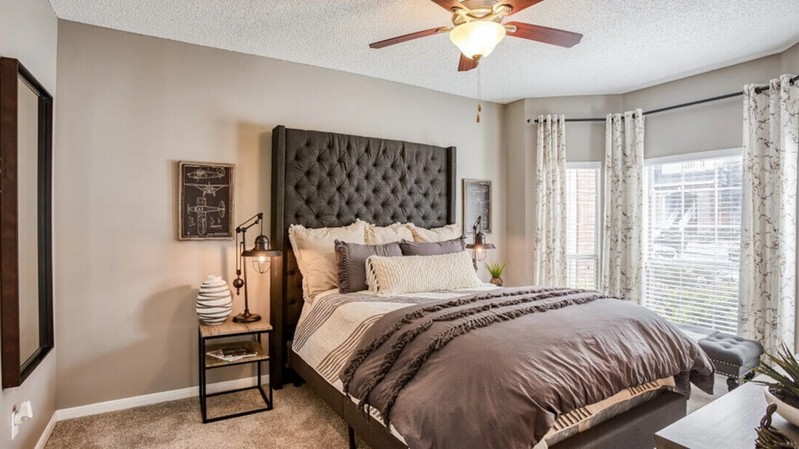 Elegant bedroom with plush upholstered bed, stylish lighting, and natural light streaming through large windows, creating a serene ambiance.