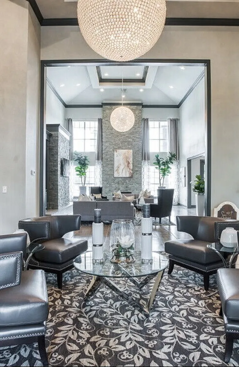 Luxurious living room featuring elegant leather seating, modern d&eacute;cor, and a stunning chandelier, perfect for stylish entertaining.