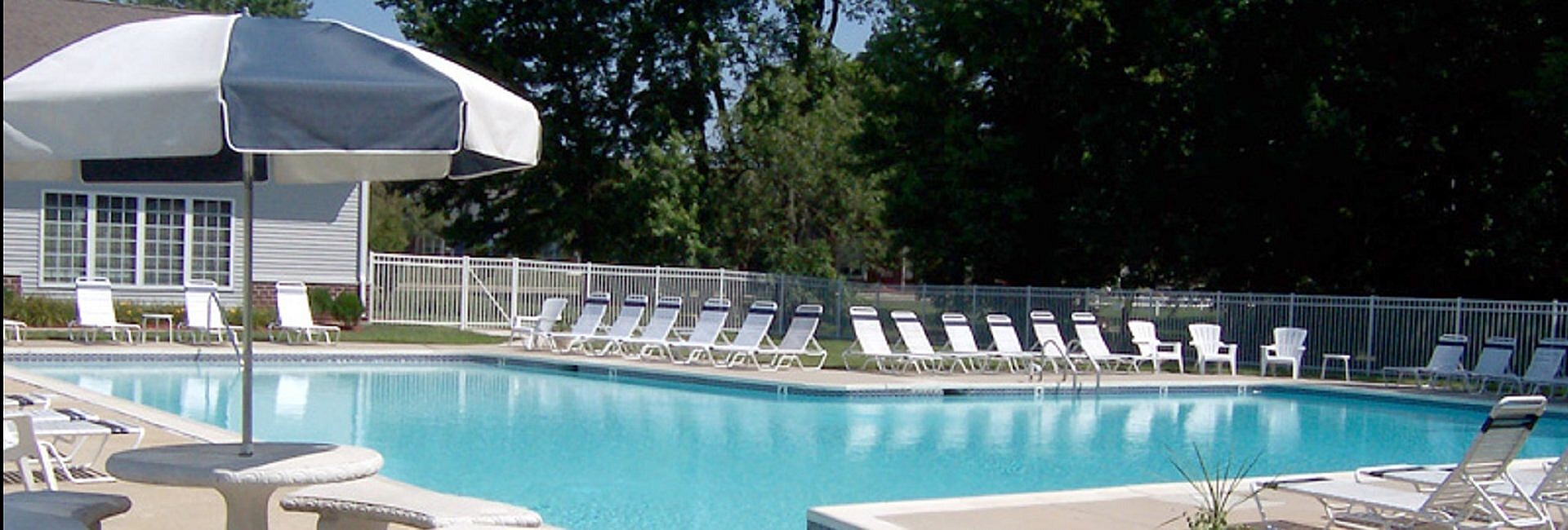 Inviting pool area featuring sparkling blue water, ample lounge chairs, and relaxing umbrella-shaded tables perfect for a sunny getaway.