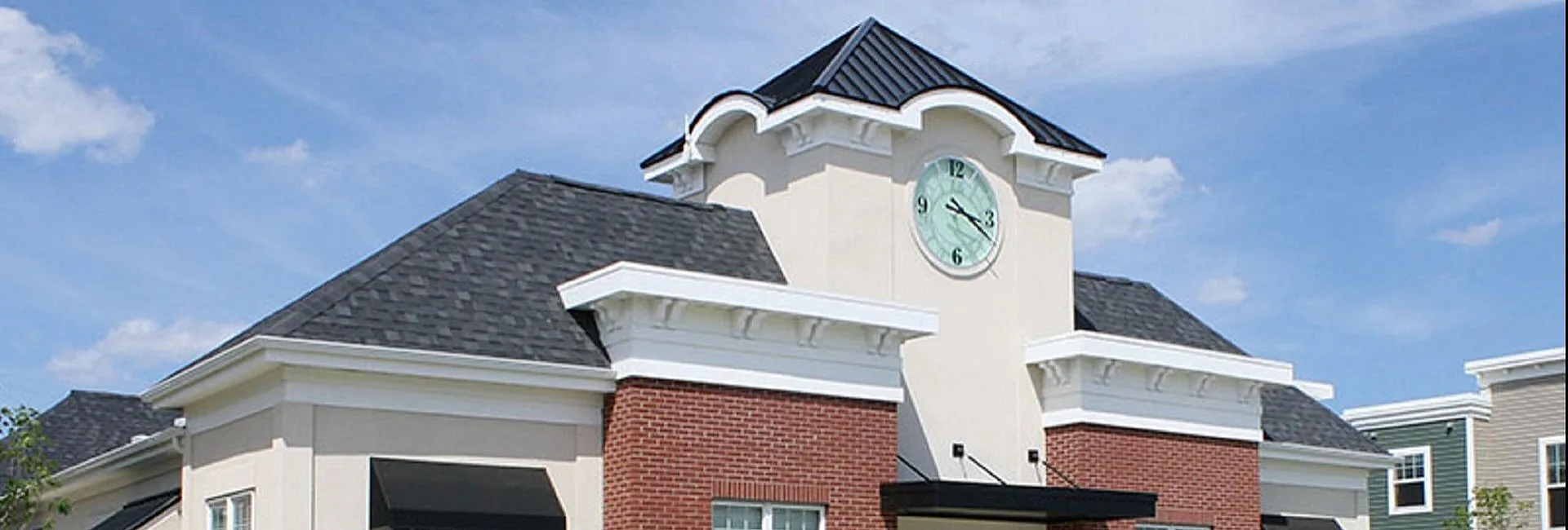 Elegant building exterior with a classic clock tower and stylish brick facade under a bright blue sky.