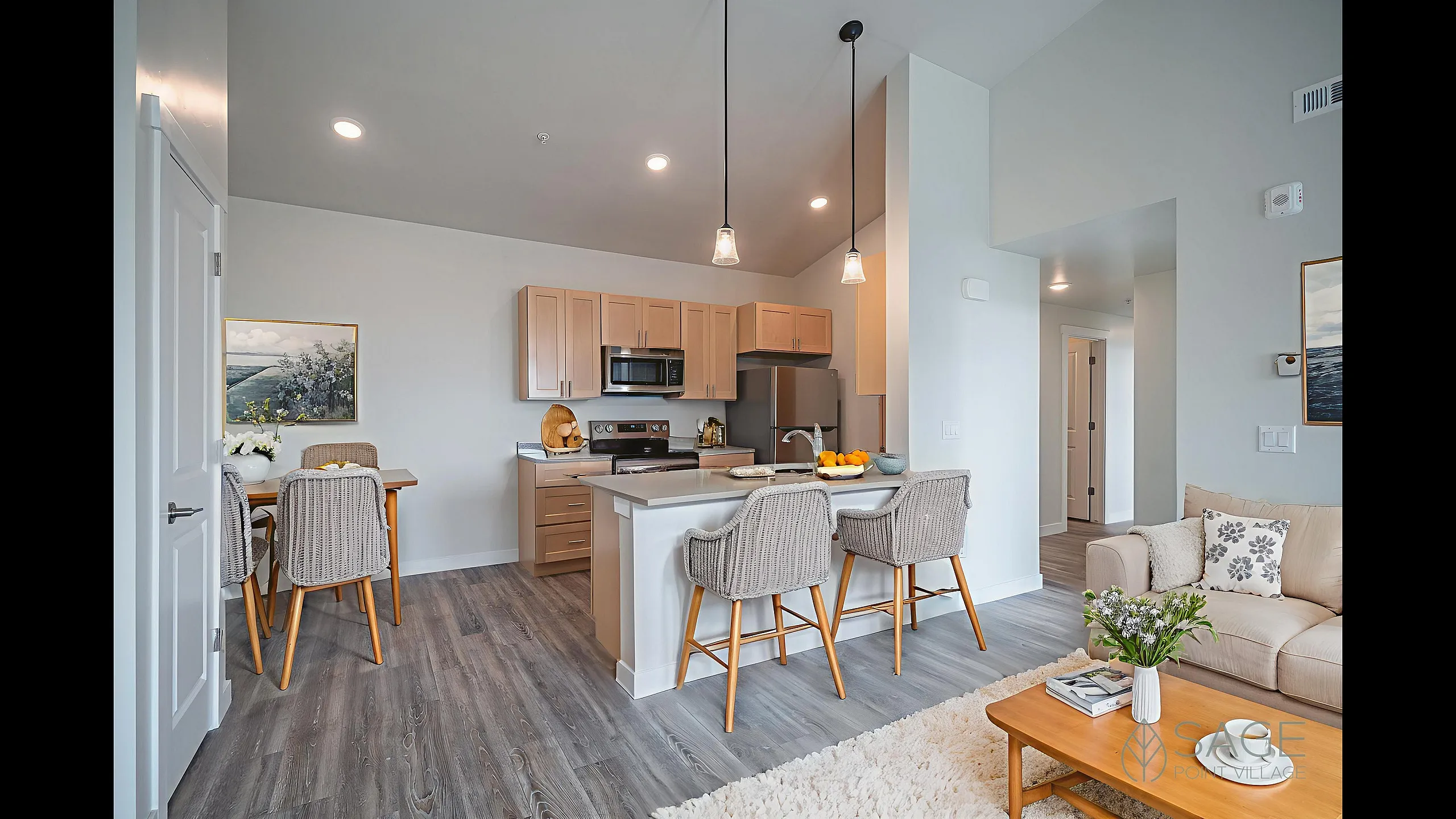 Inviting open-concept kitchen and living area with modern appliances, elegant light fixtures, and cozy seating, ideal for entertaining.