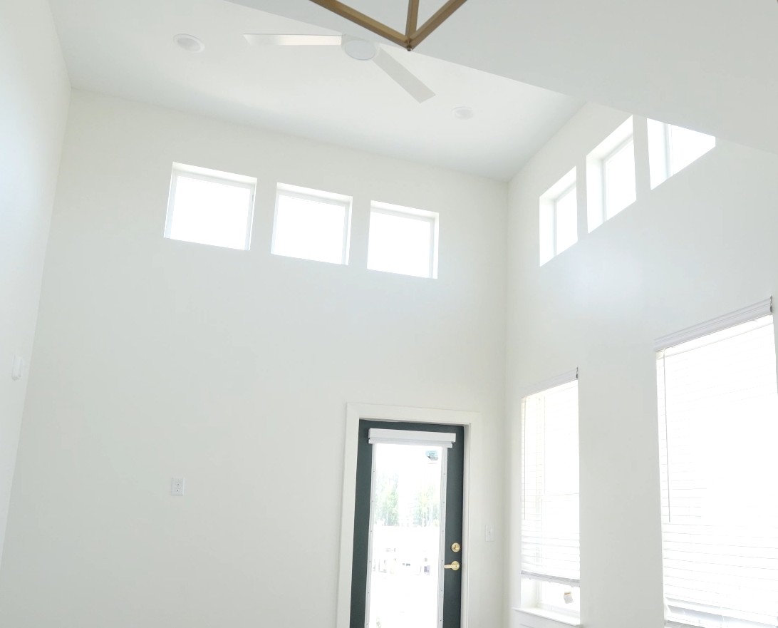 Bright and airy living space with high ceilings and abundant natural light filtering through multiple windows.