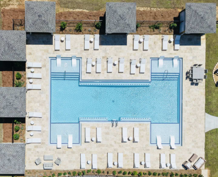 Luxurious apartment complex features a stunning aerial view of a large swimming pool surrounded by stylish sun loungers and cozy cabanas, perfect for relaxation and leisure.