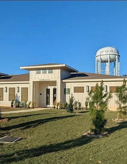 Charming modern building with clean lines and a welcoming entrance, set against a clear blue sky, surrounded by beautifully landscaped greenery.