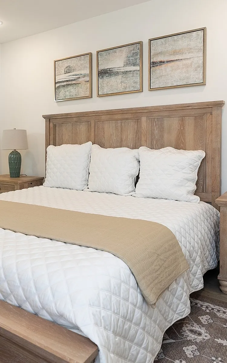 Elegant bedroom featuring a cozy queen-sized bed with plush bedding, warm wooden furniture, and soft lighting for a serene atmosphere.